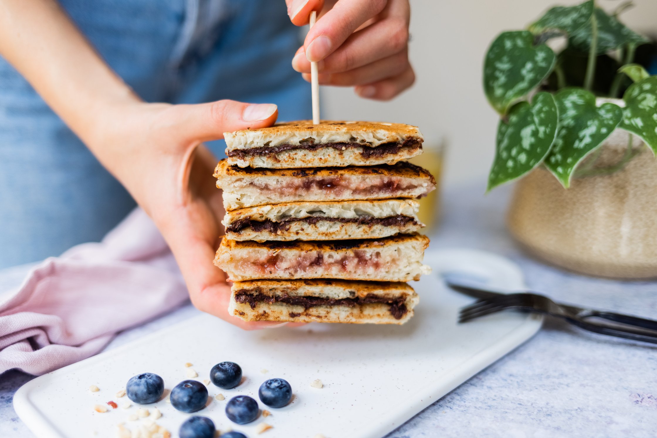 vegan filled pancakes stacked, stabilized with a skewer, blueberries, plant