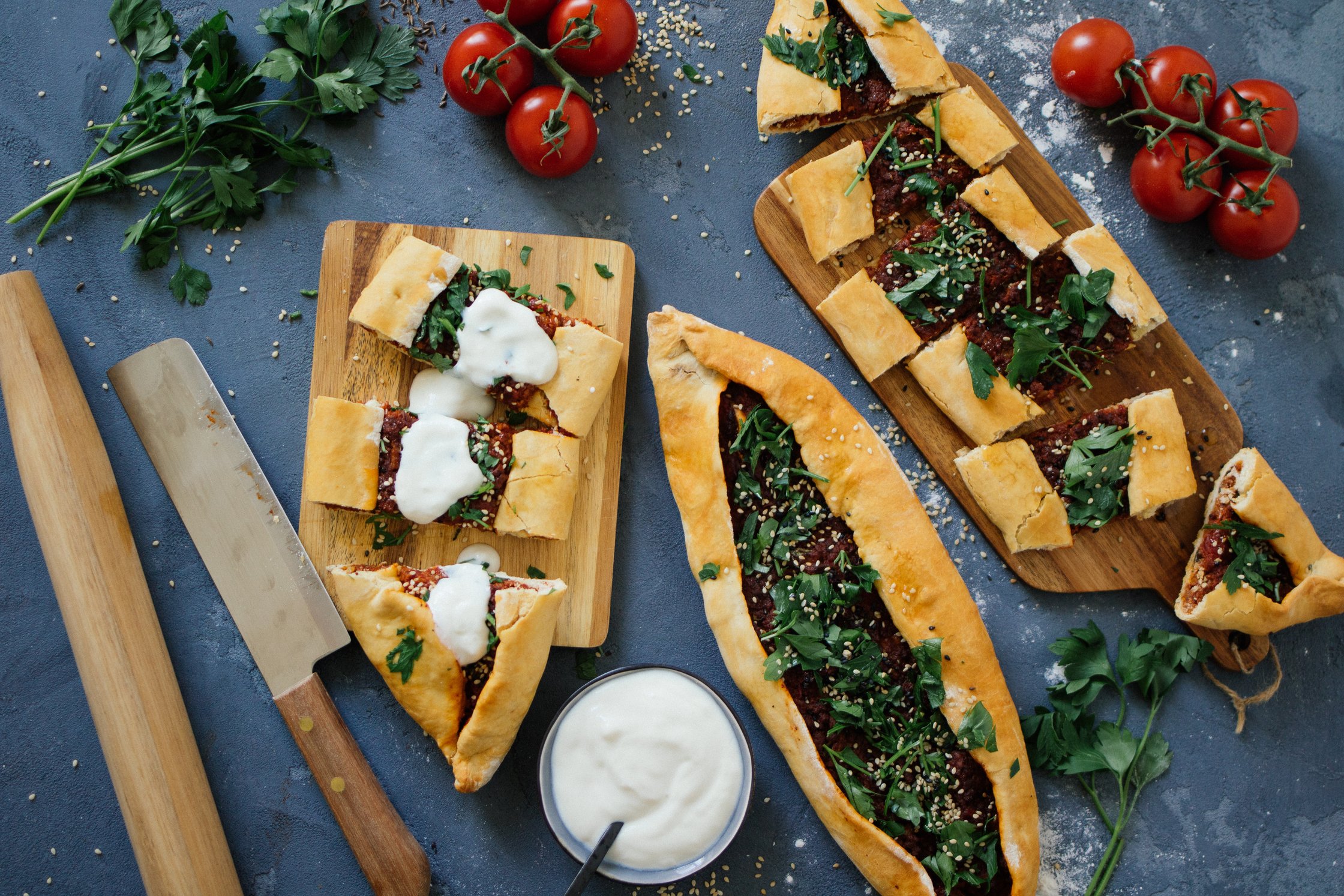 sliced pide next to tomatoes and parsley