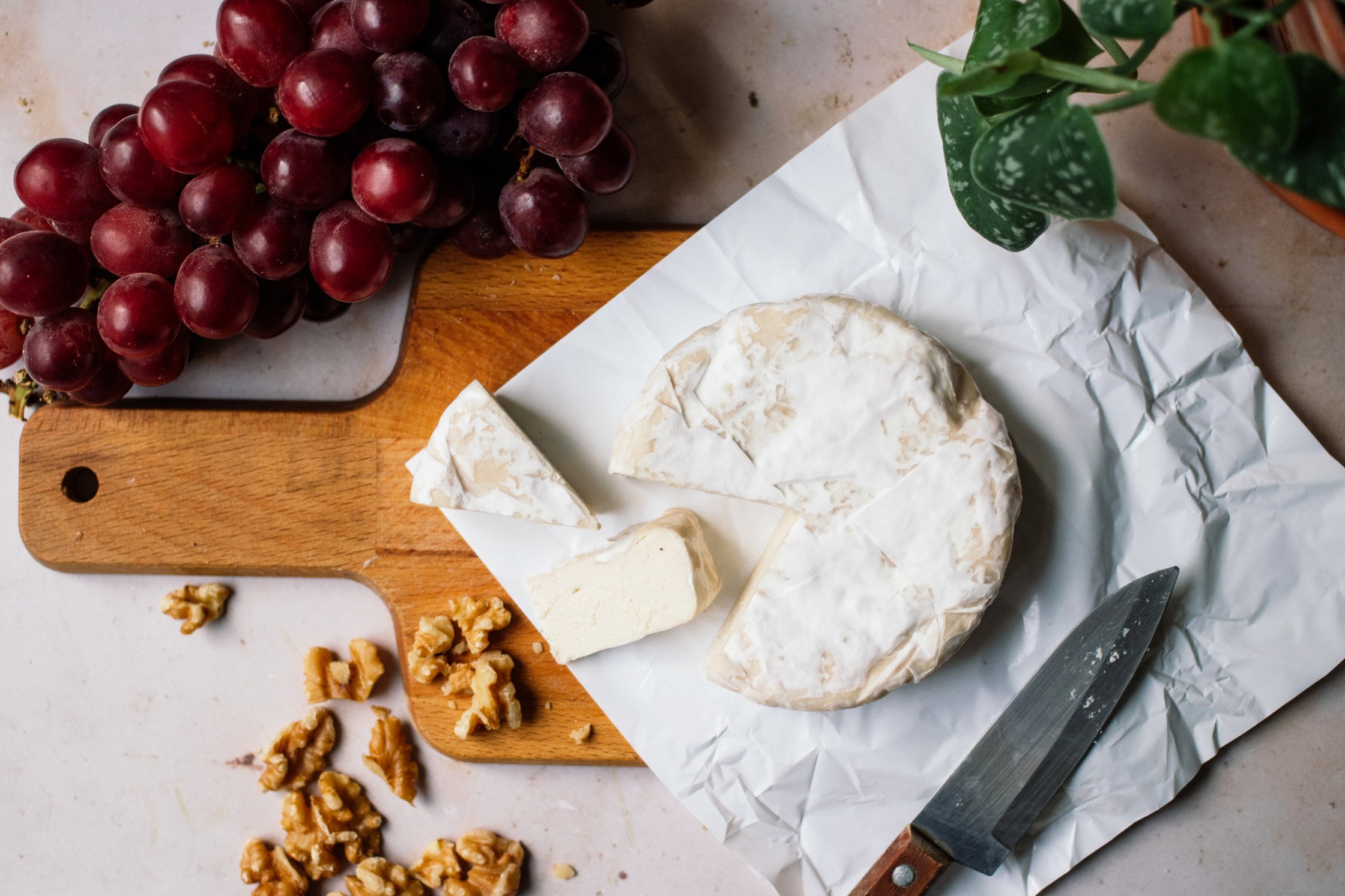 cut vegan camembert with grapes and walnuts