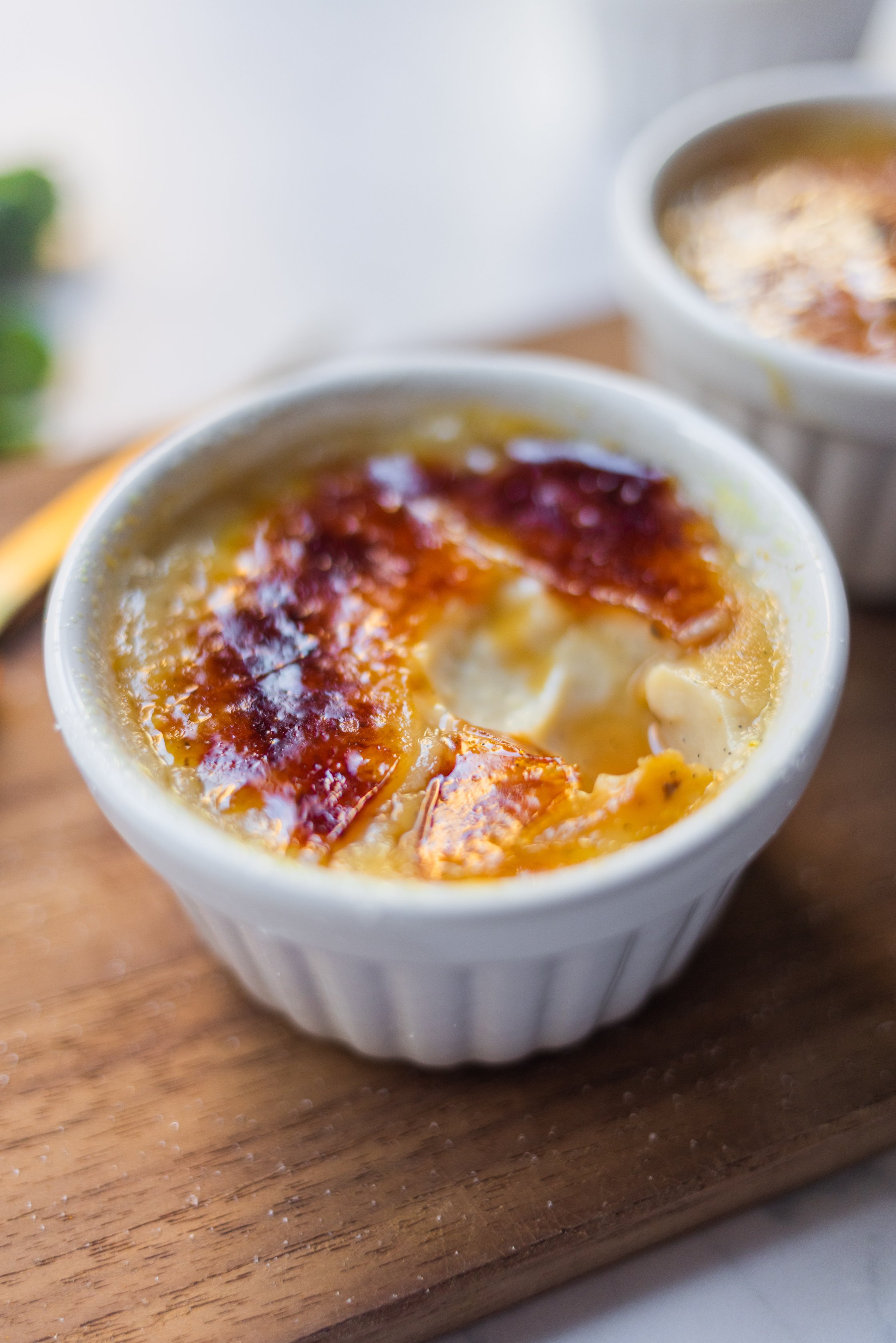 Creme brulee in white bowls on a wooden board.