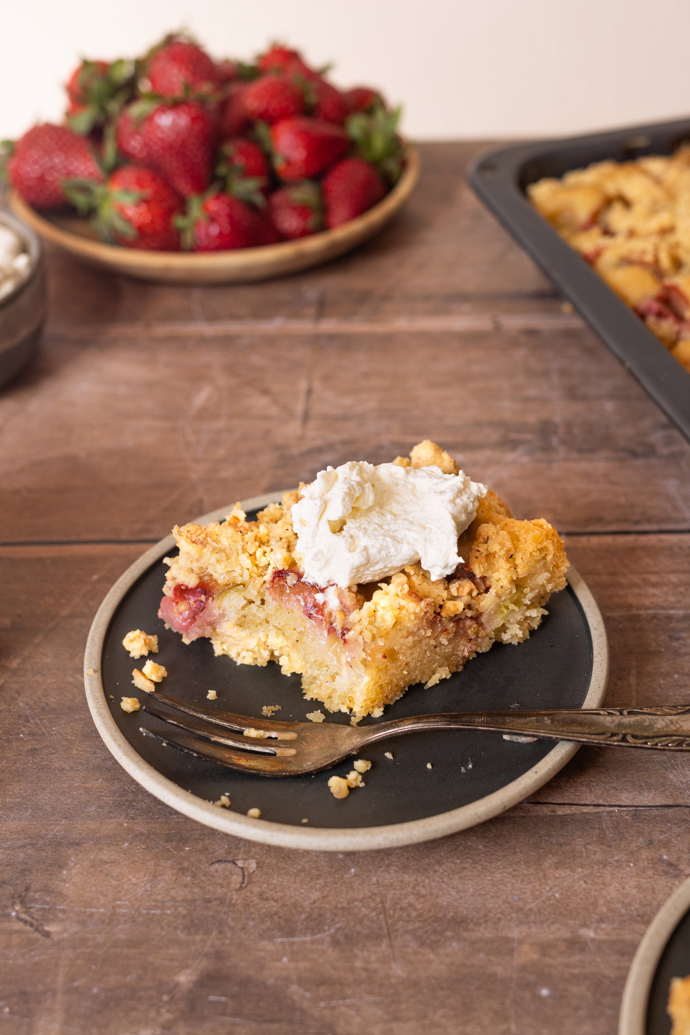 Rhabarber-Erdbeer-Kuchen serviert mit veganer Sahne.