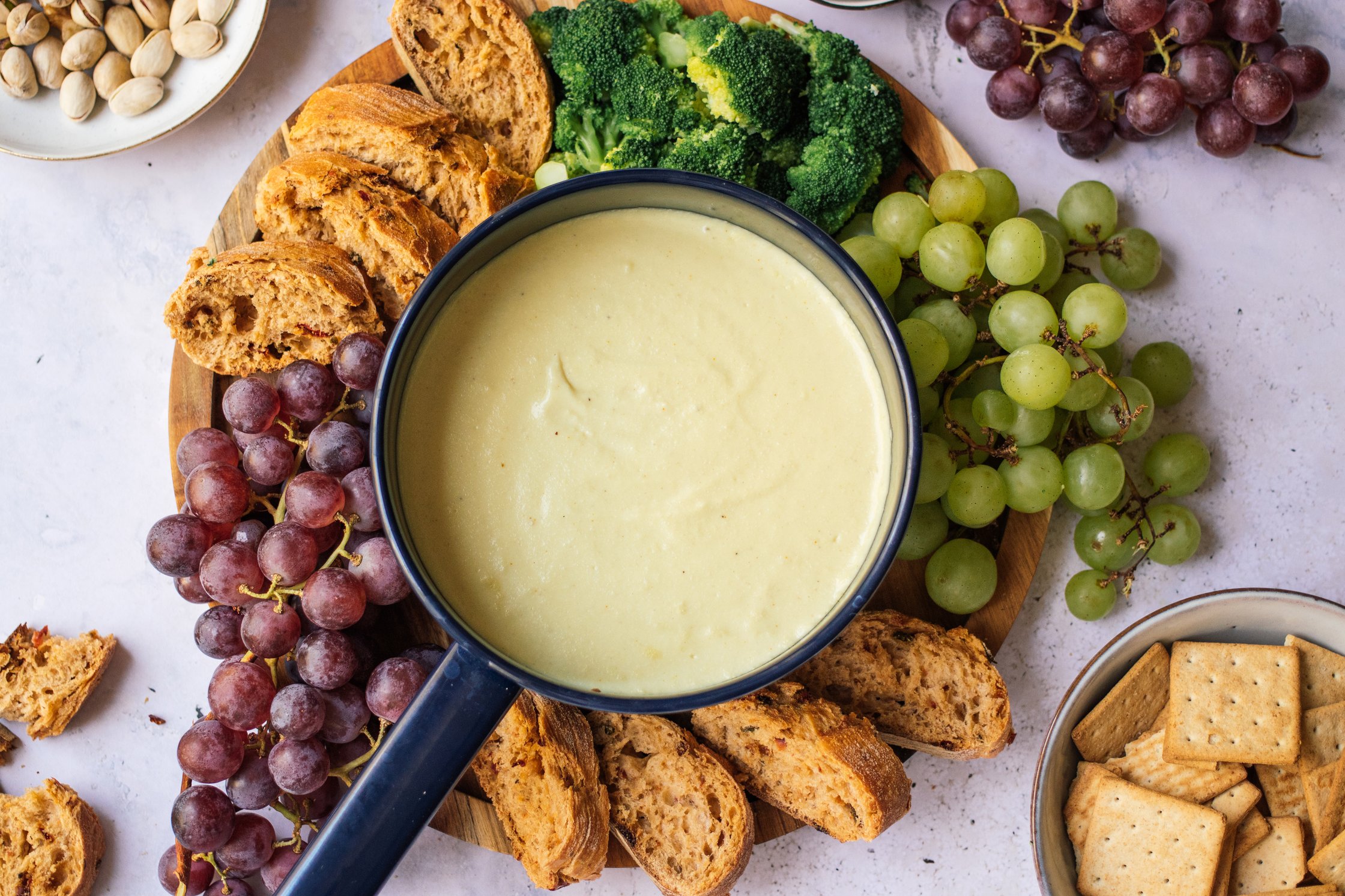 vegan cheese fondue with bread, vegetables, and fruits