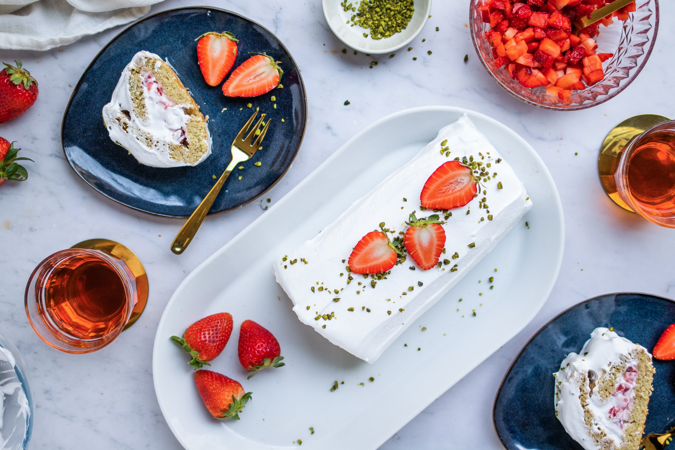 Vegane Biskuitrolle mit Sahne und Erdbeeren auf Tellern mit Tee