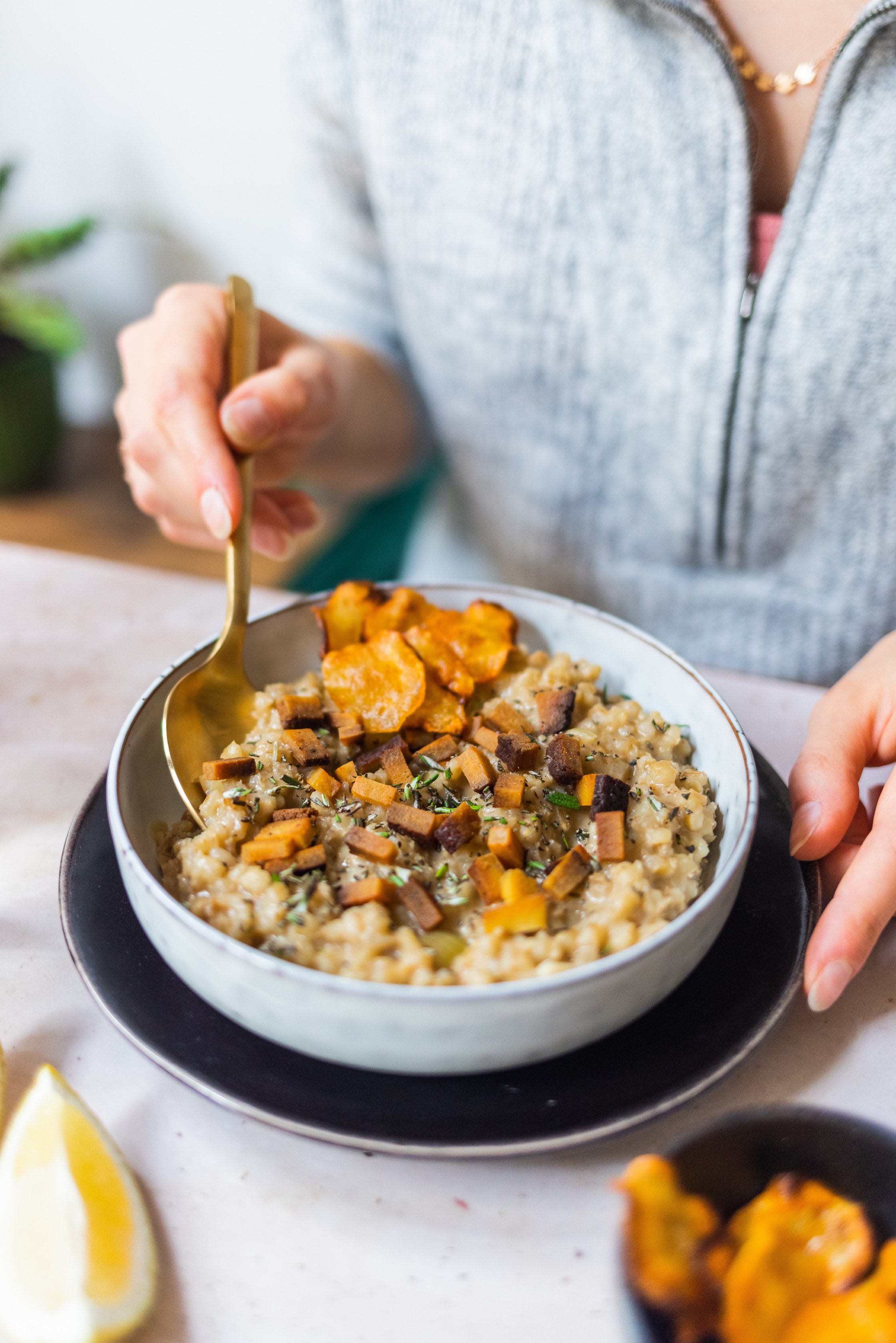 Veganes Gerstenrisotto mit Topinamburchips wird aus einer weißen Schüssel gegessen