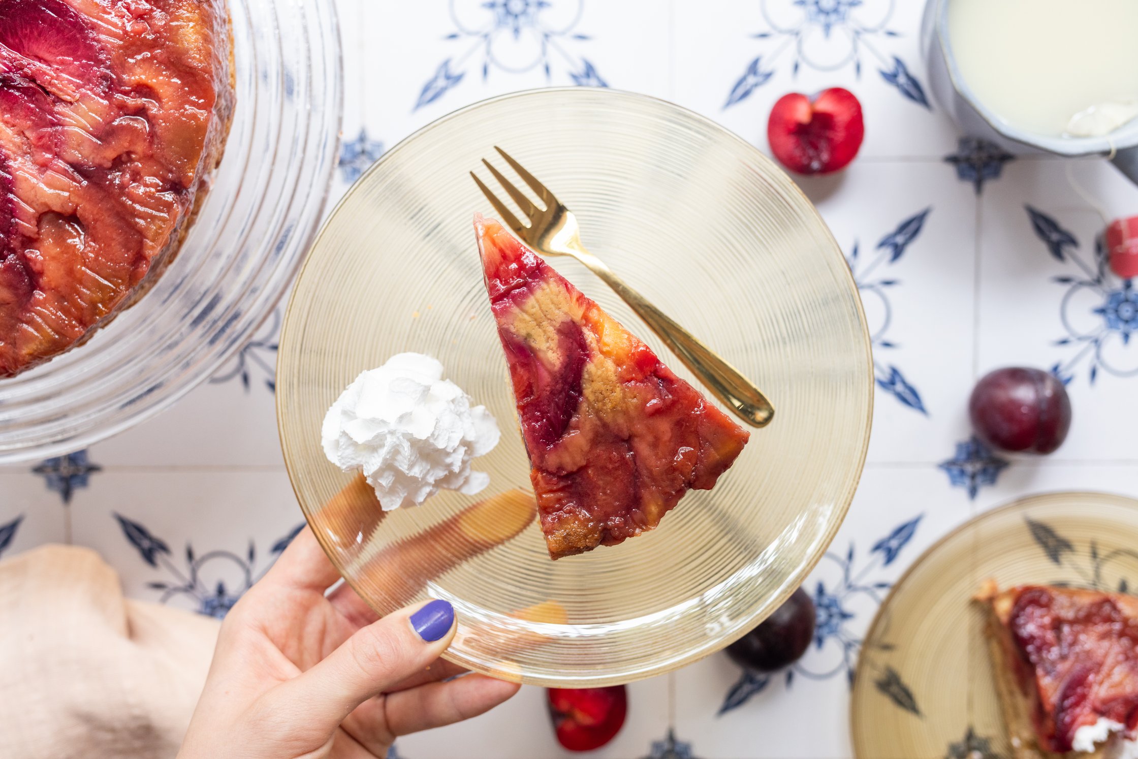 Here, a piece of the cake is arranged on a glass plate with whipped cream.
