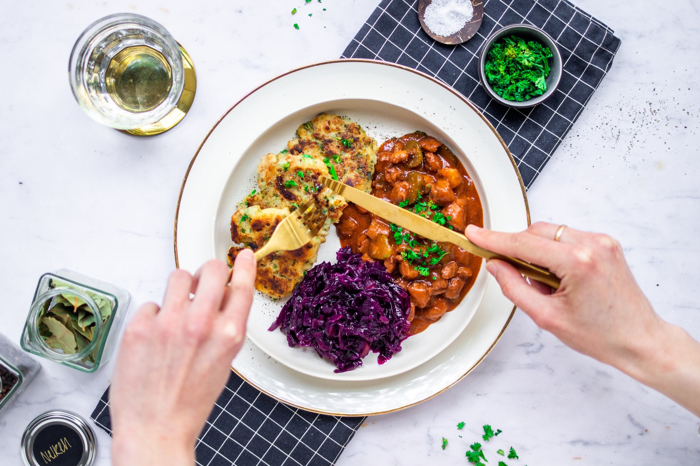 Vegan goulash with pan dumplings and red cabbage is arranged on a plate and eaten.