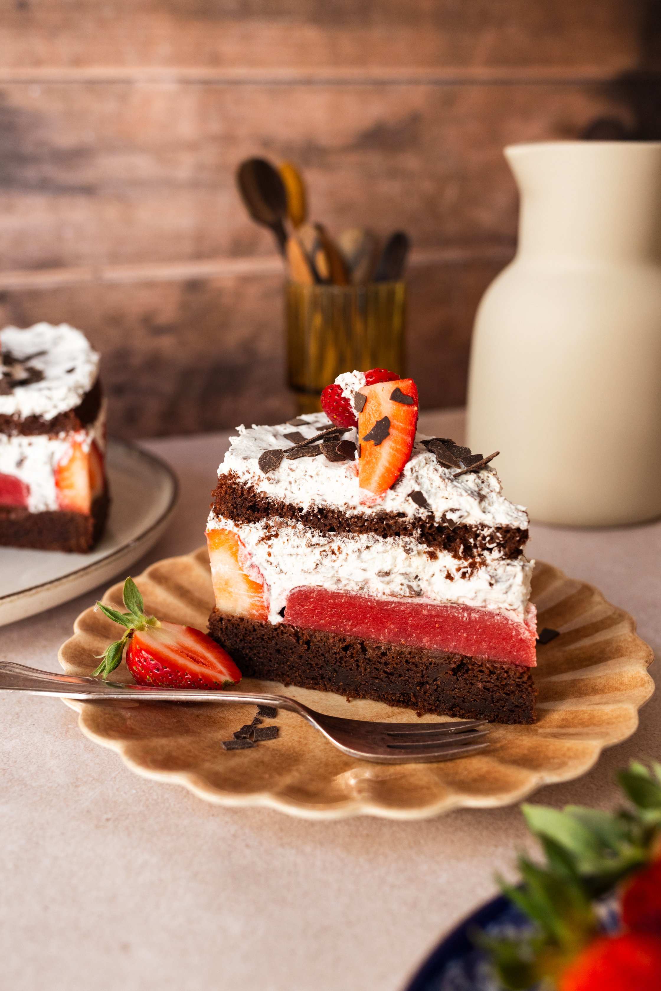 Hier ist ein angerichtetes Stück Torte, auf einem Muschelförmigen Teller abgebildet.