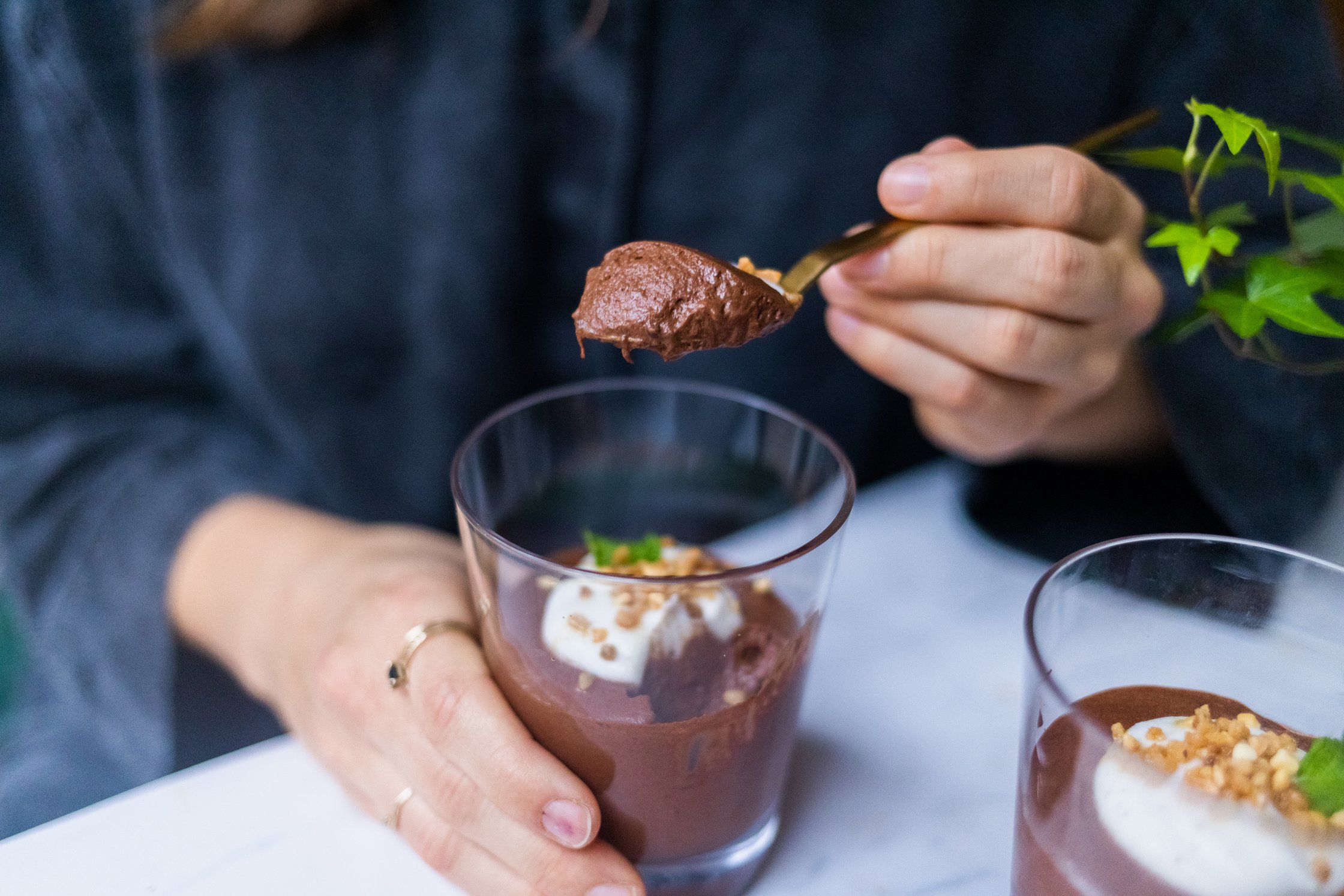 Vegane Mousse au Chocolat wird aus einem Dessertglas gelöffelt.