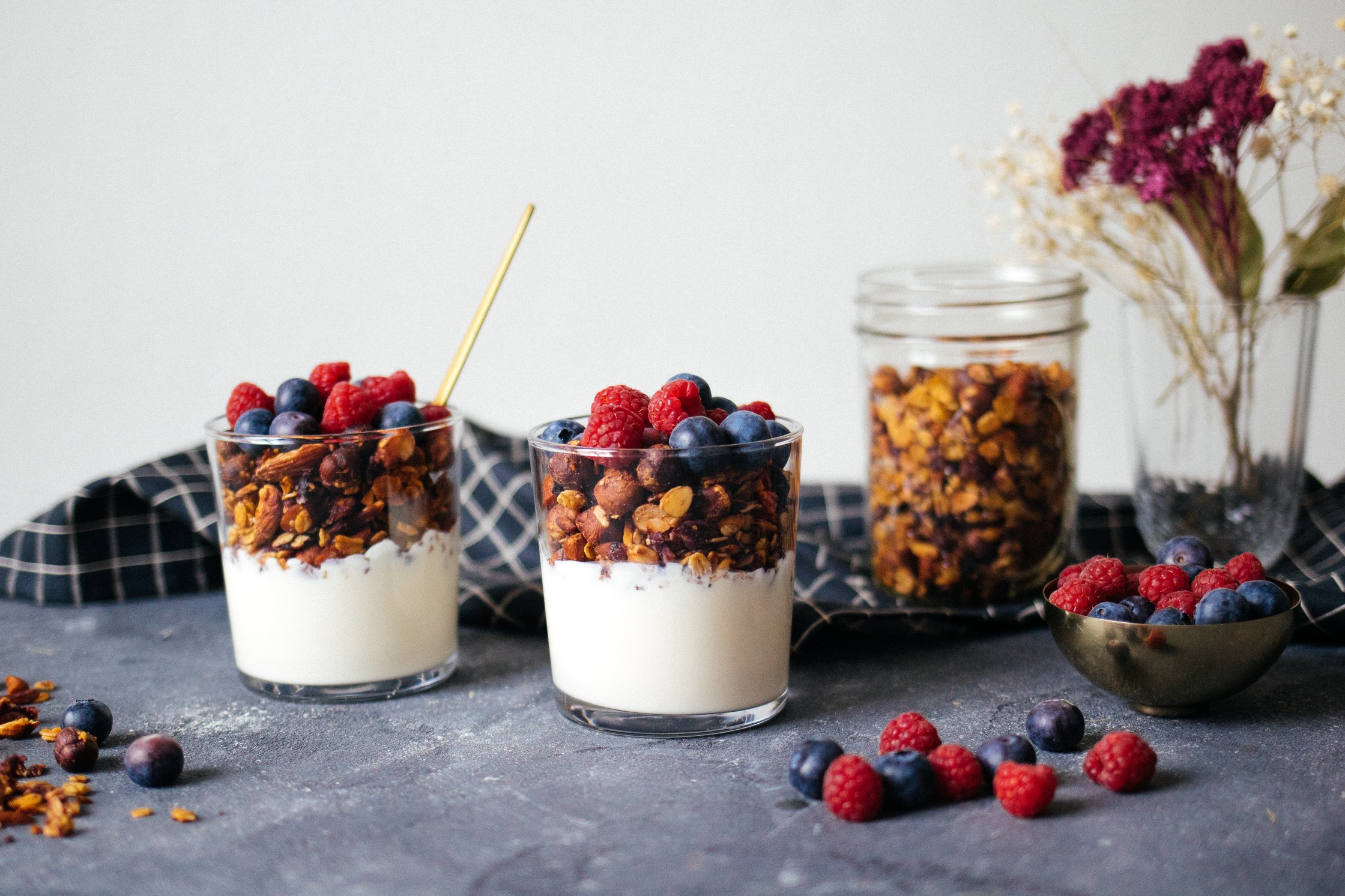 zwei Gläser gefüllt mit Beeren, Joghurt und Granola