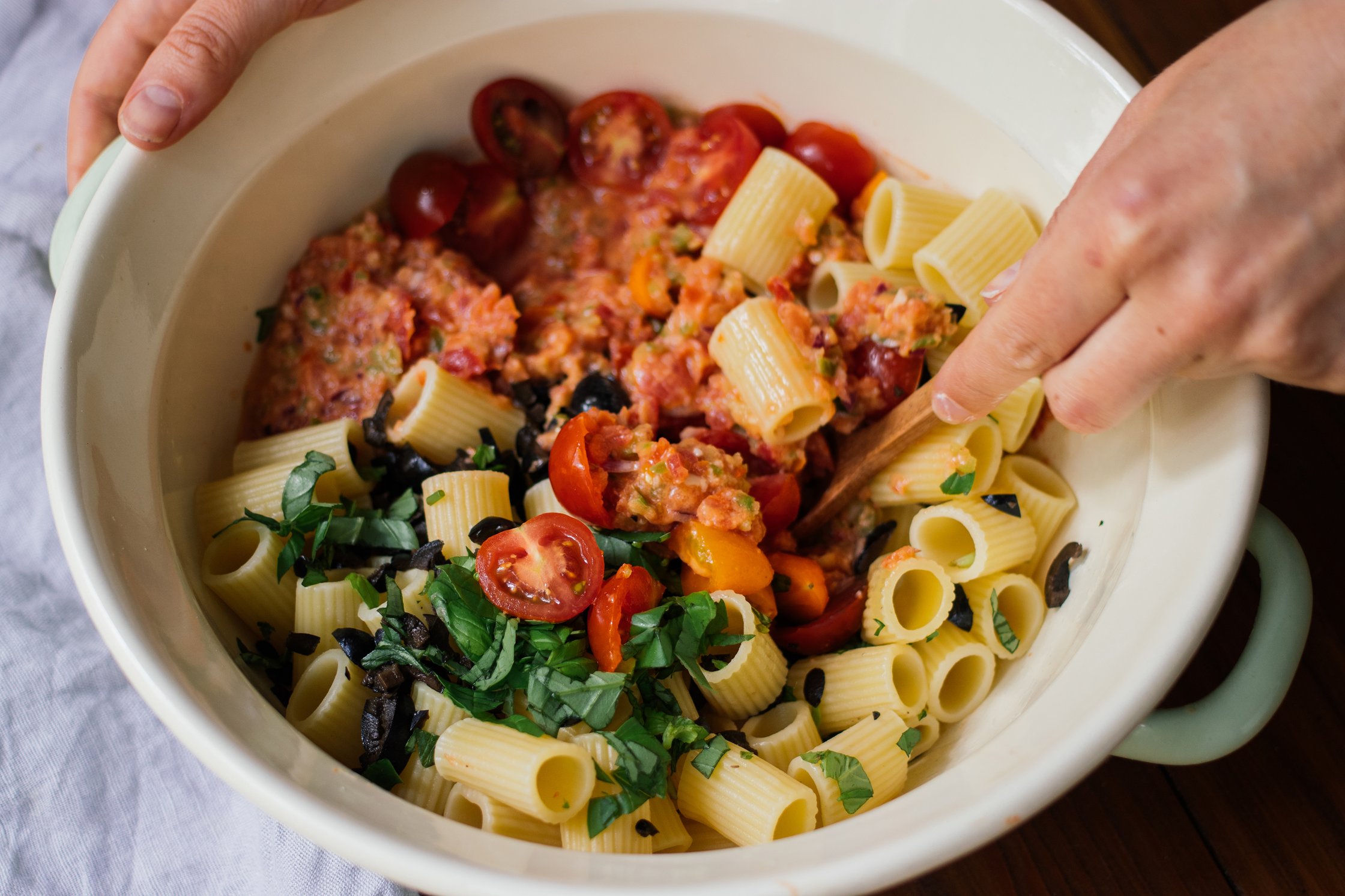 mixing the ingredients for gazpacho pasta in a bowl