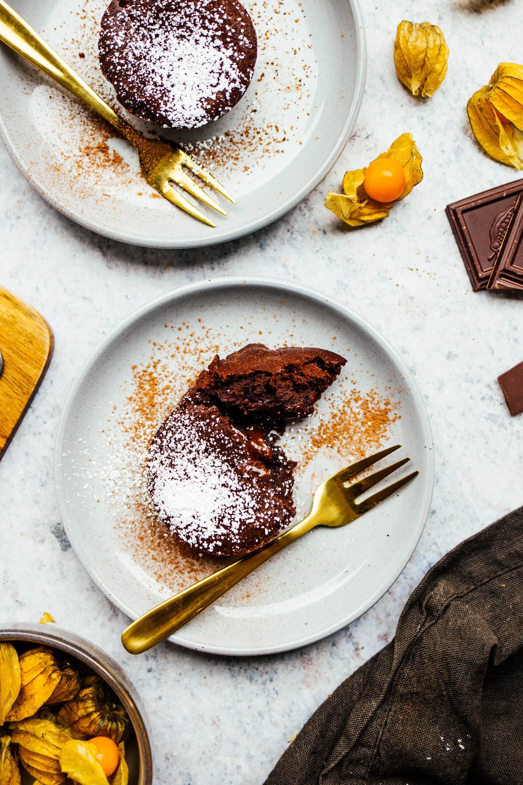 Vegane Lava Cakes von oben auf Tellern mit Phyalis und goldenen Gäbelchen