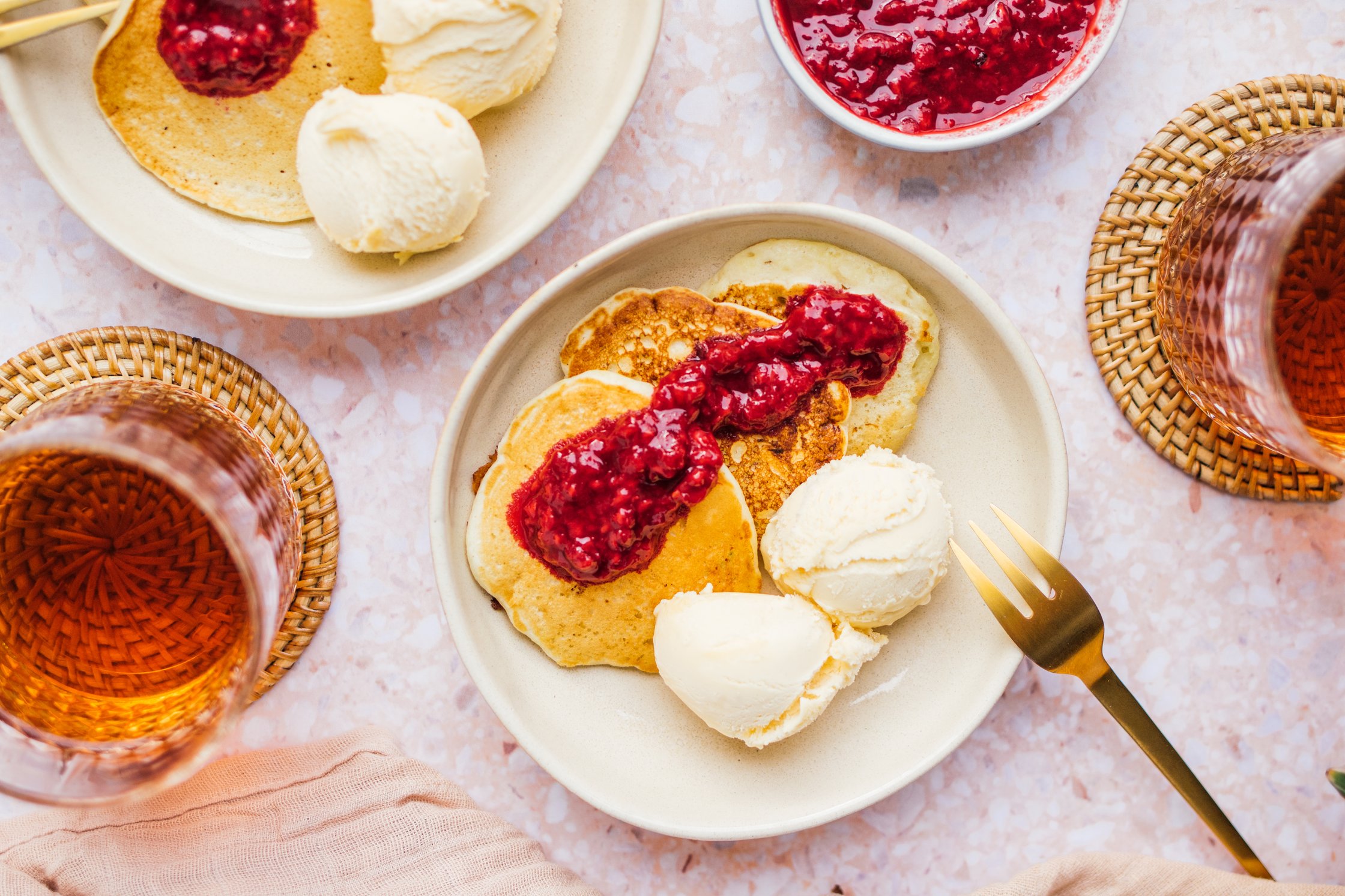 Tiefer Teller mit drei veganen Pancakes, heißen Himbeeren und veganem Vanille Eis