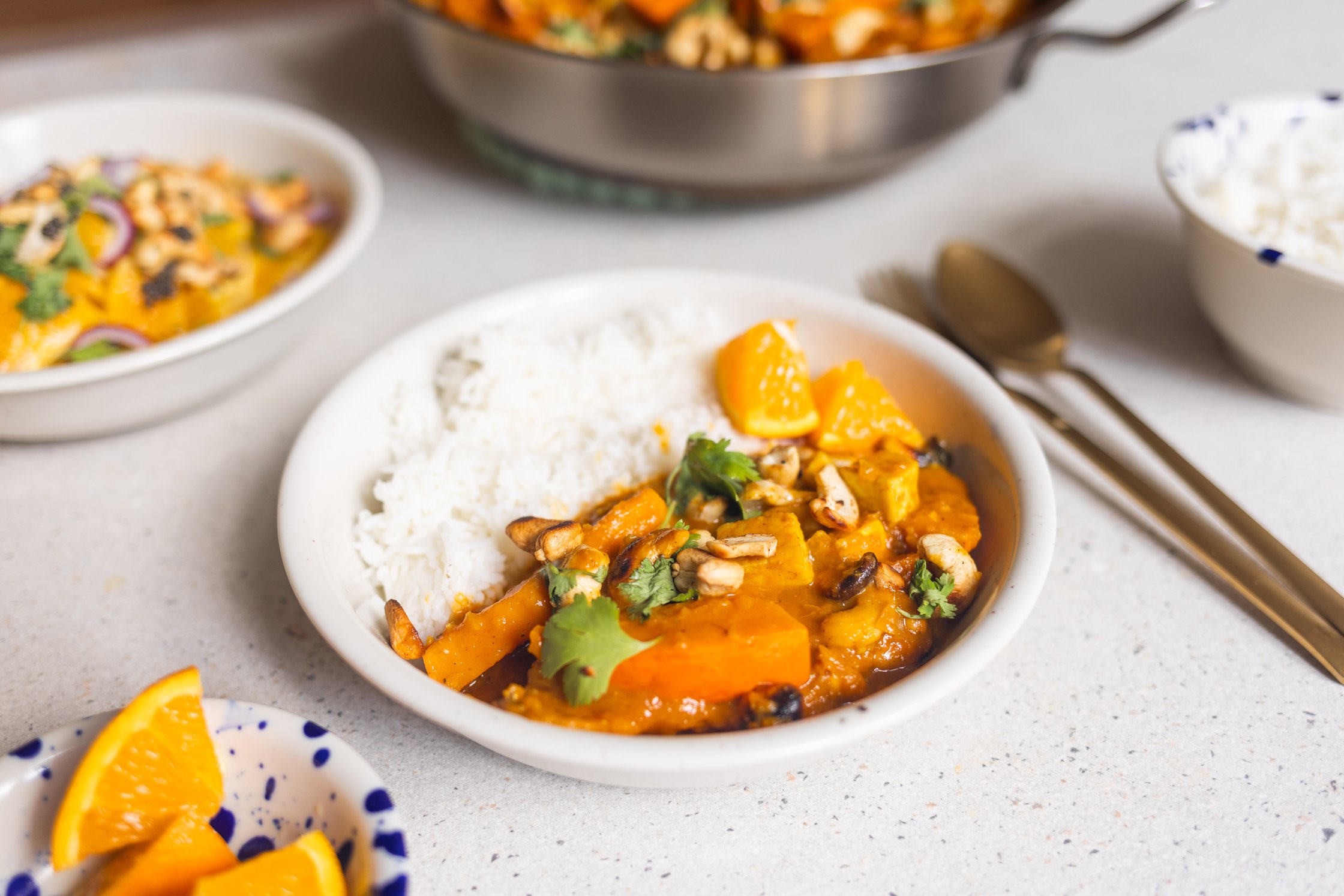 Vegan curry with plant-based protein served over white rice in bowls with fresh garnish and orange wedges