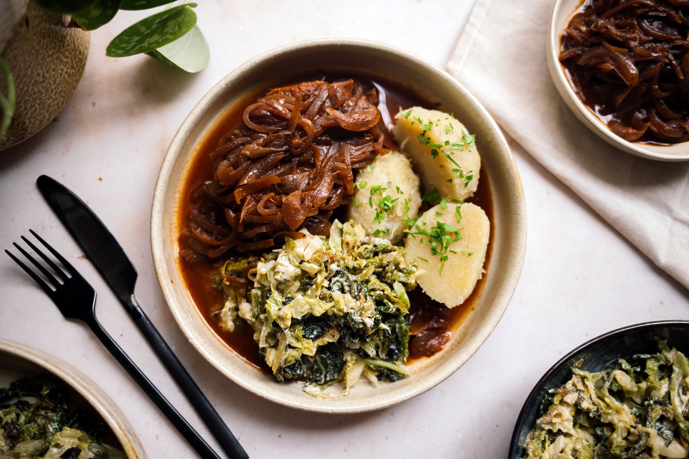 Grüne Klöße mit Zwiebelrostseitan und veganem Rahmwirsing servierbereit
