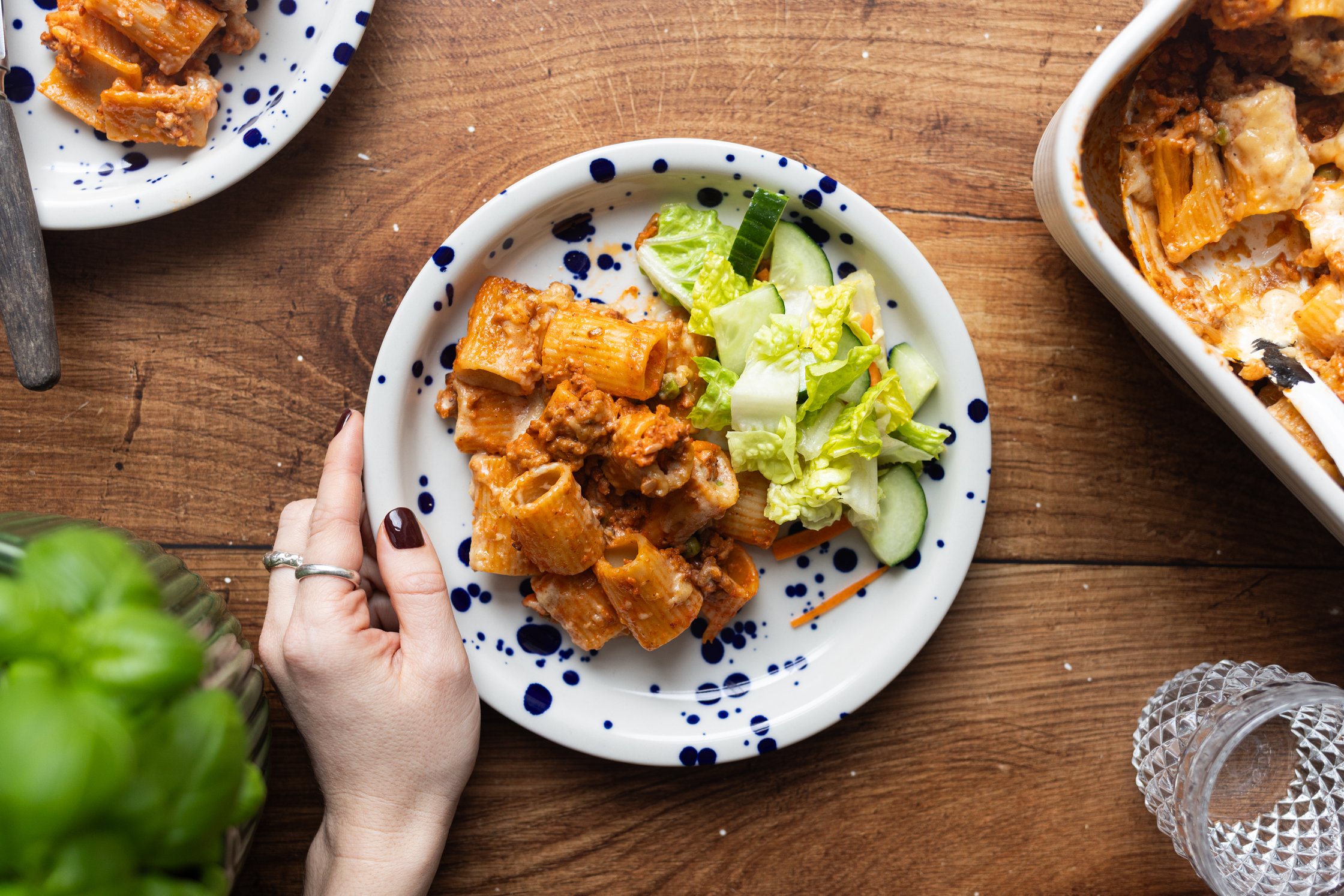 Rigatoni al Forno mit Erbsen auf einem Teller mit Salat serviert.