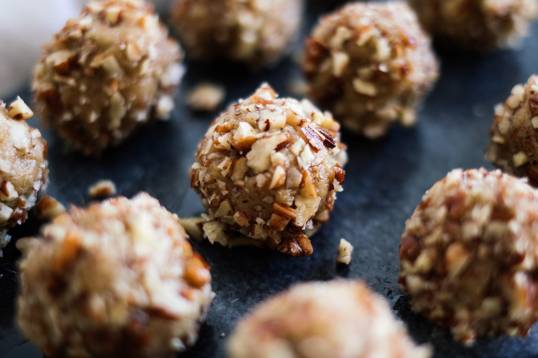 vegane Käsebällchen liegen  angeordnet auf braunem Brett