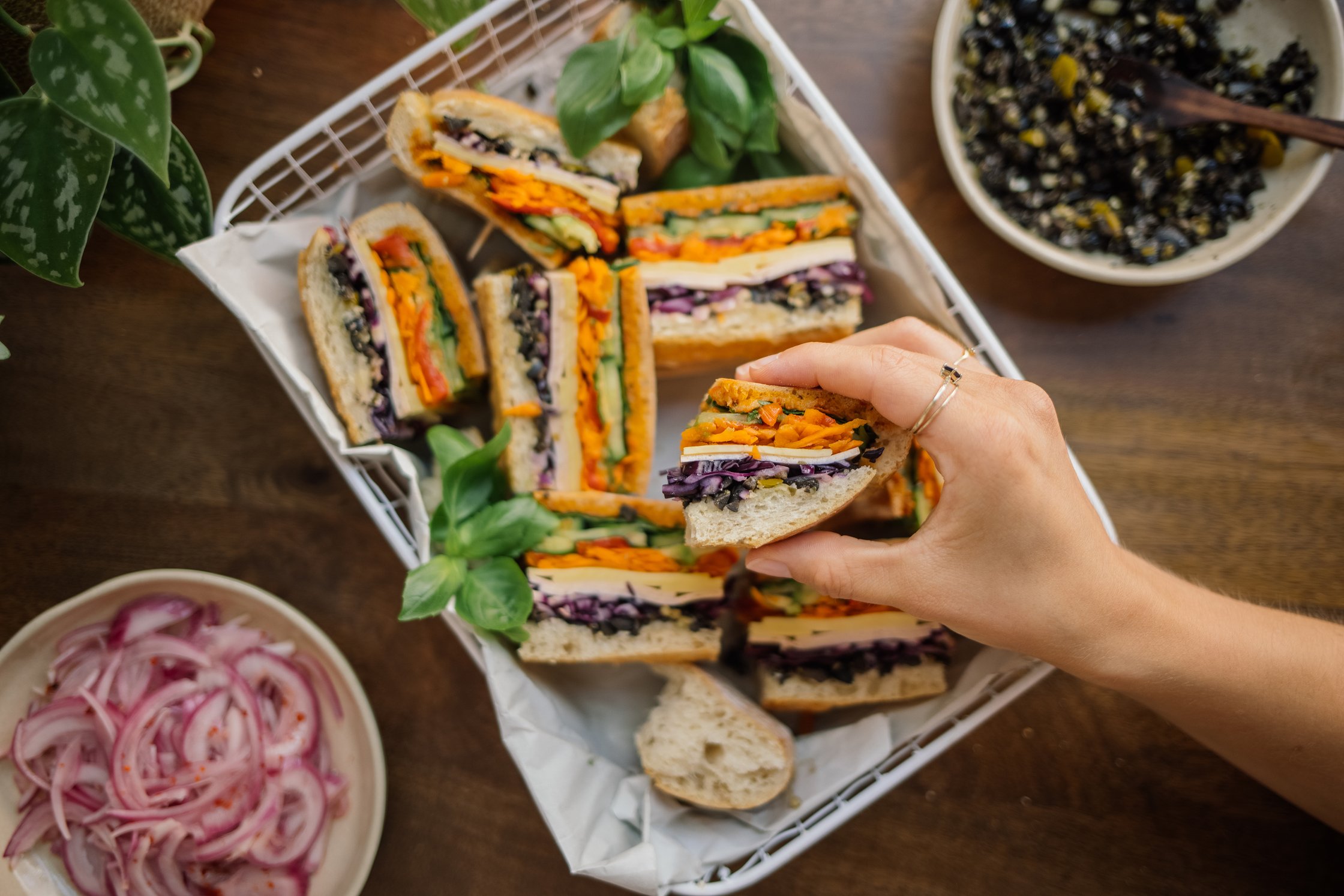a hand grabs a piece of vegan muffuletta sandwich