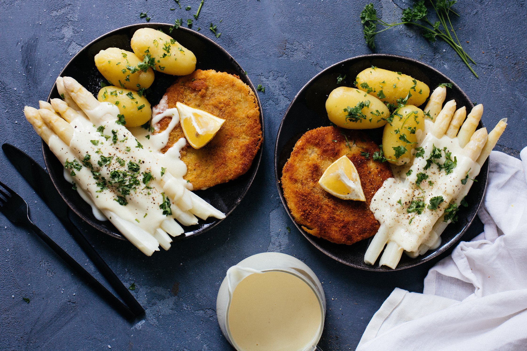 two plates with asparagus, potatoes and schnitzel