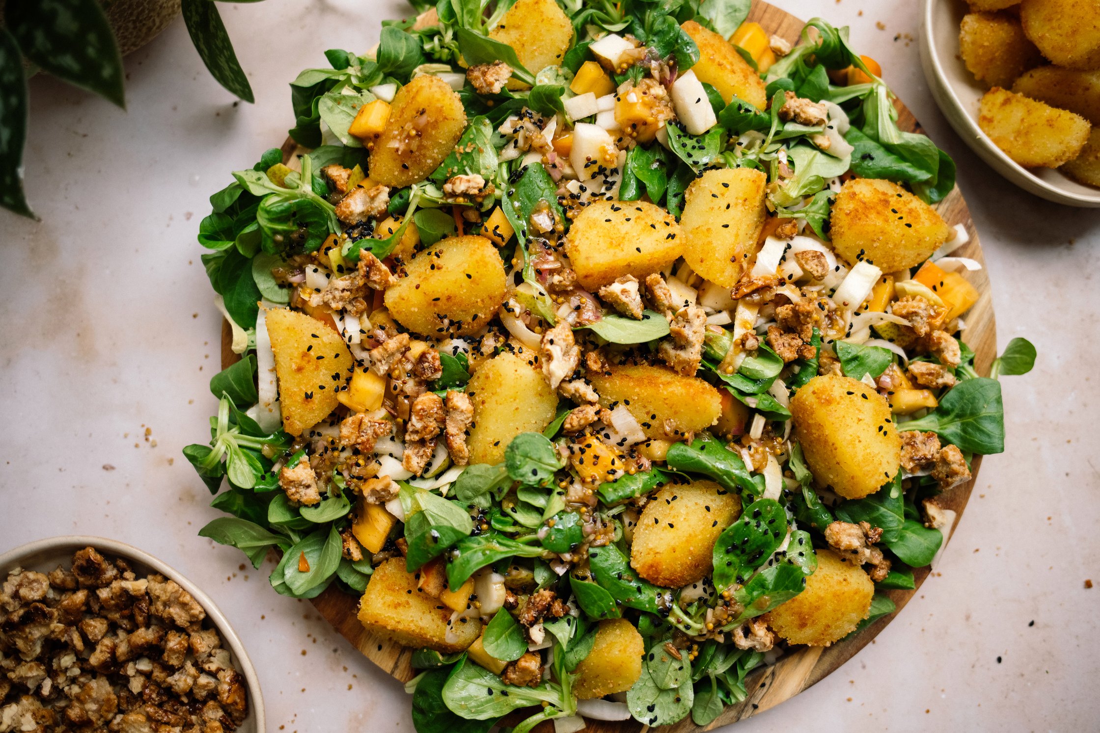 Chicory and Lamb's Lettuce Salad with Pear, Persimmon and Dumpling Croutons on a platter