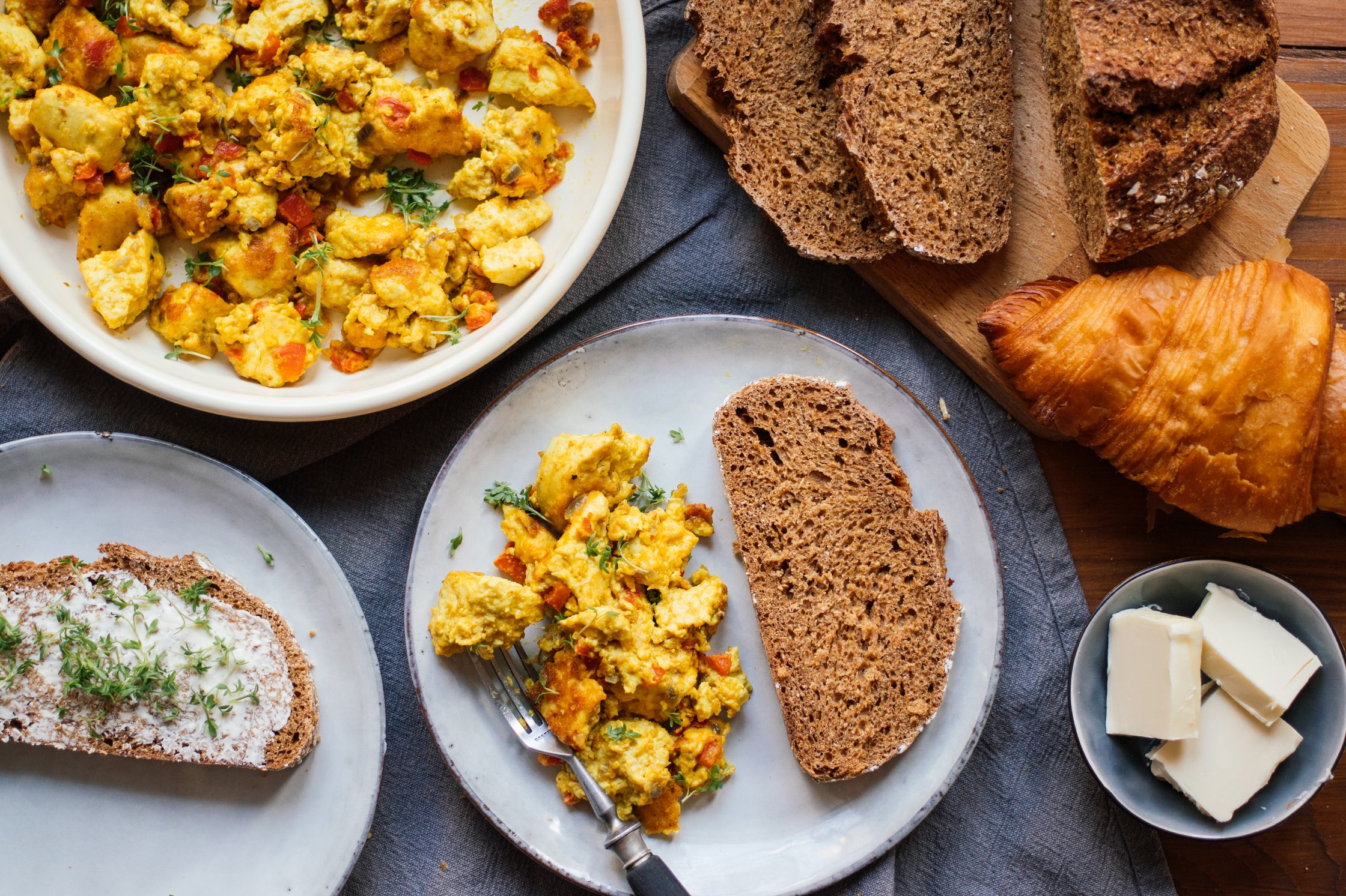 frühstückstisch mit veganem rührei, brot und croissant
