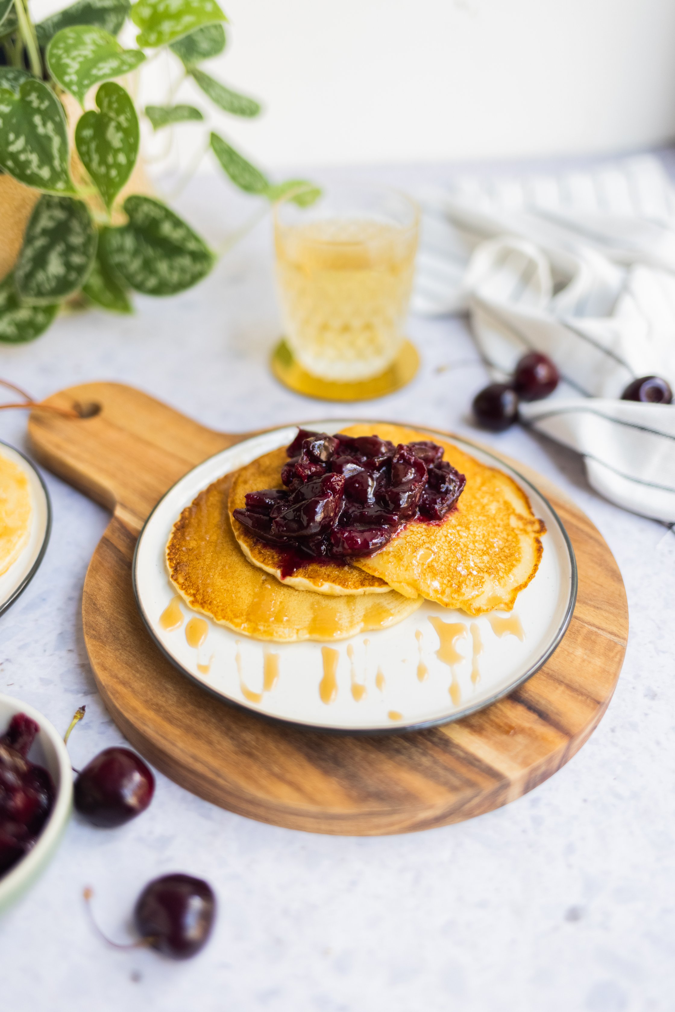 Vegan buttermilk blintzes with cherry compote, a plant in the background and a glass of tea