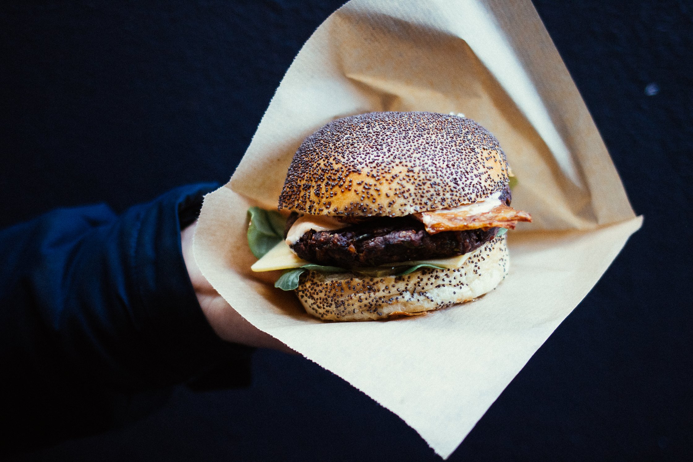 eine Hand hält einen Burger in braunem Papier