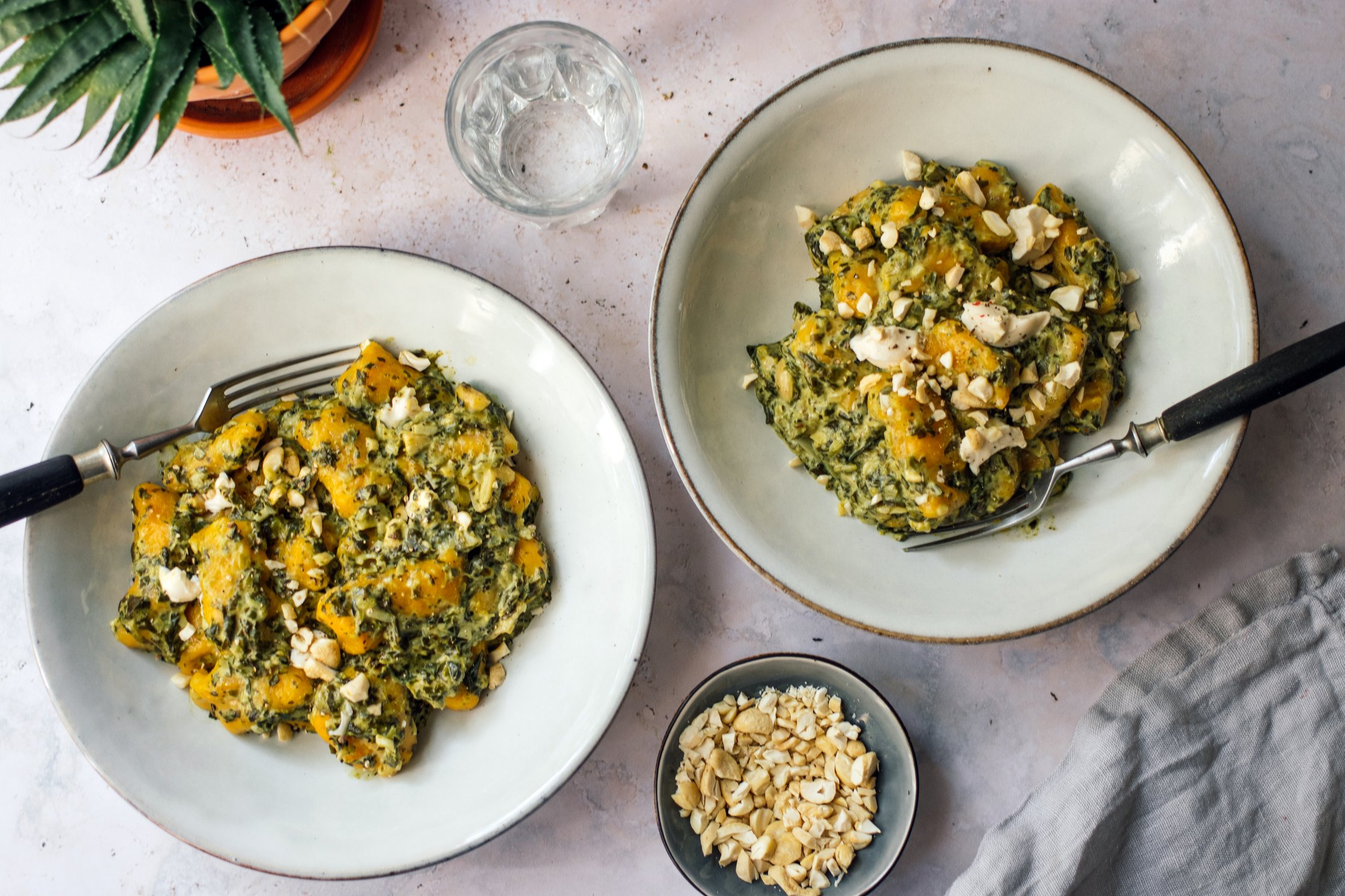 zwei teller Vegane Kürbisgnocchi mit cremiger Spinat-Frischkäse-Soße