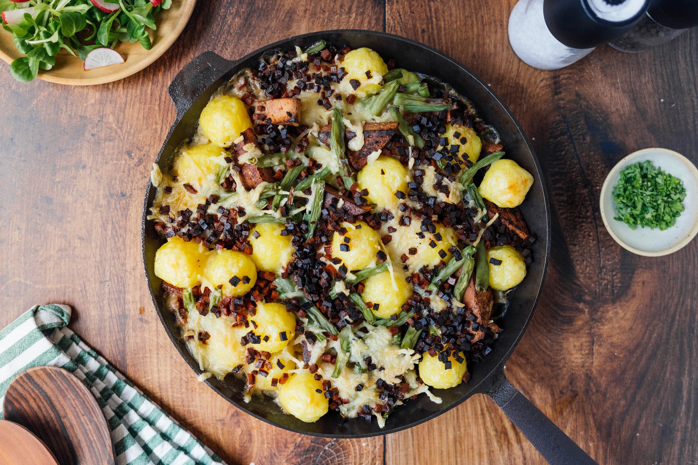 veganer Knödelauflauf mit Leberkäse und Sauerkraut in einer gusseisernen Pfanne