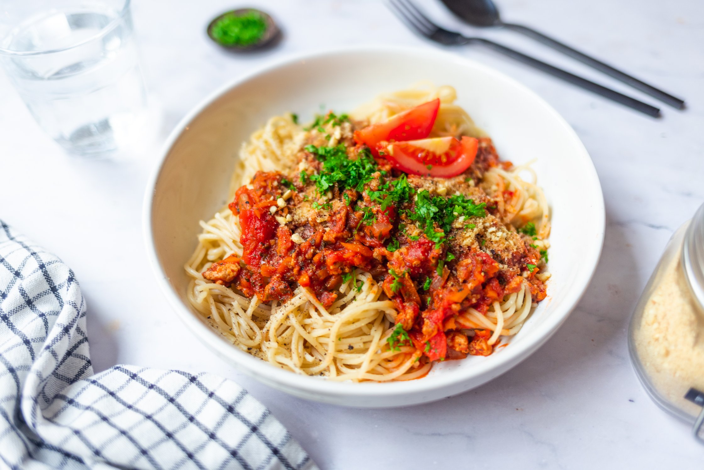 A plate with vegan spaghetti bolognese on a light background