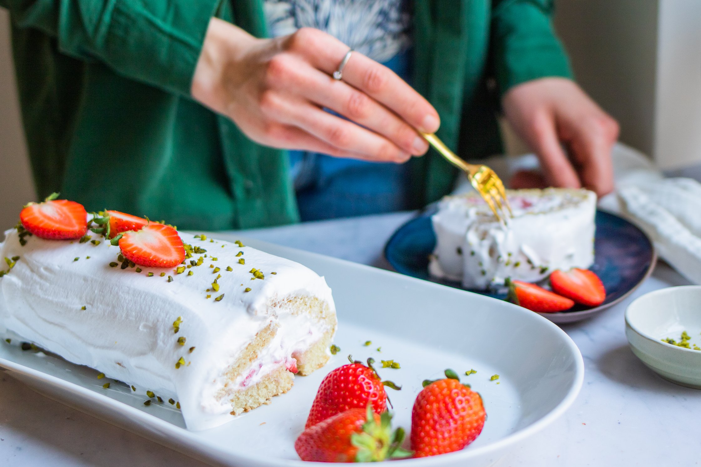 Angeschnittene Biskuitrolle gefüllt mit veganer Sahen und Erdbeeren