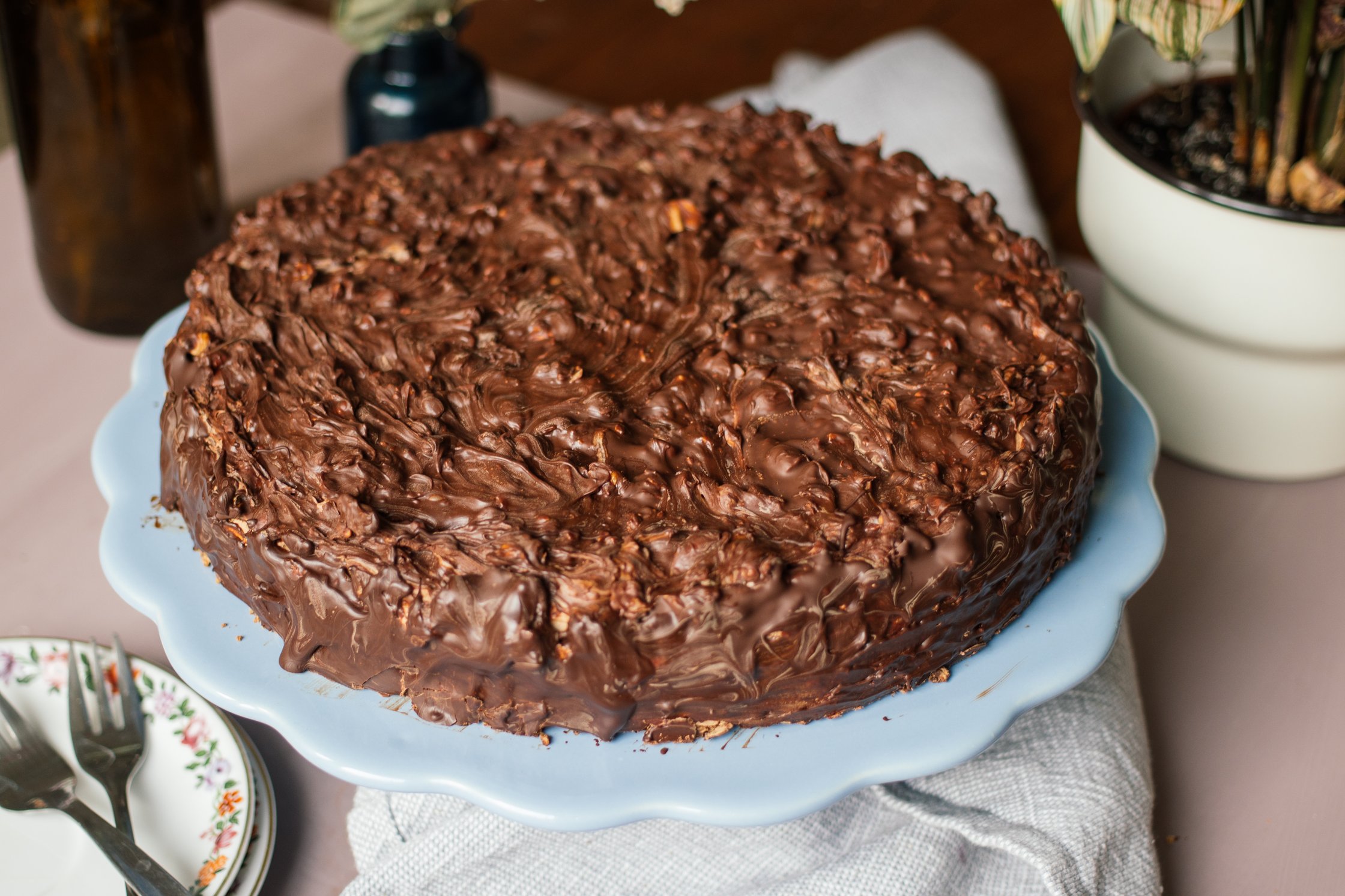 Vegane Mandeltorte mit Nougatcreme und Erdnüssen serviert auf kuchenplatte