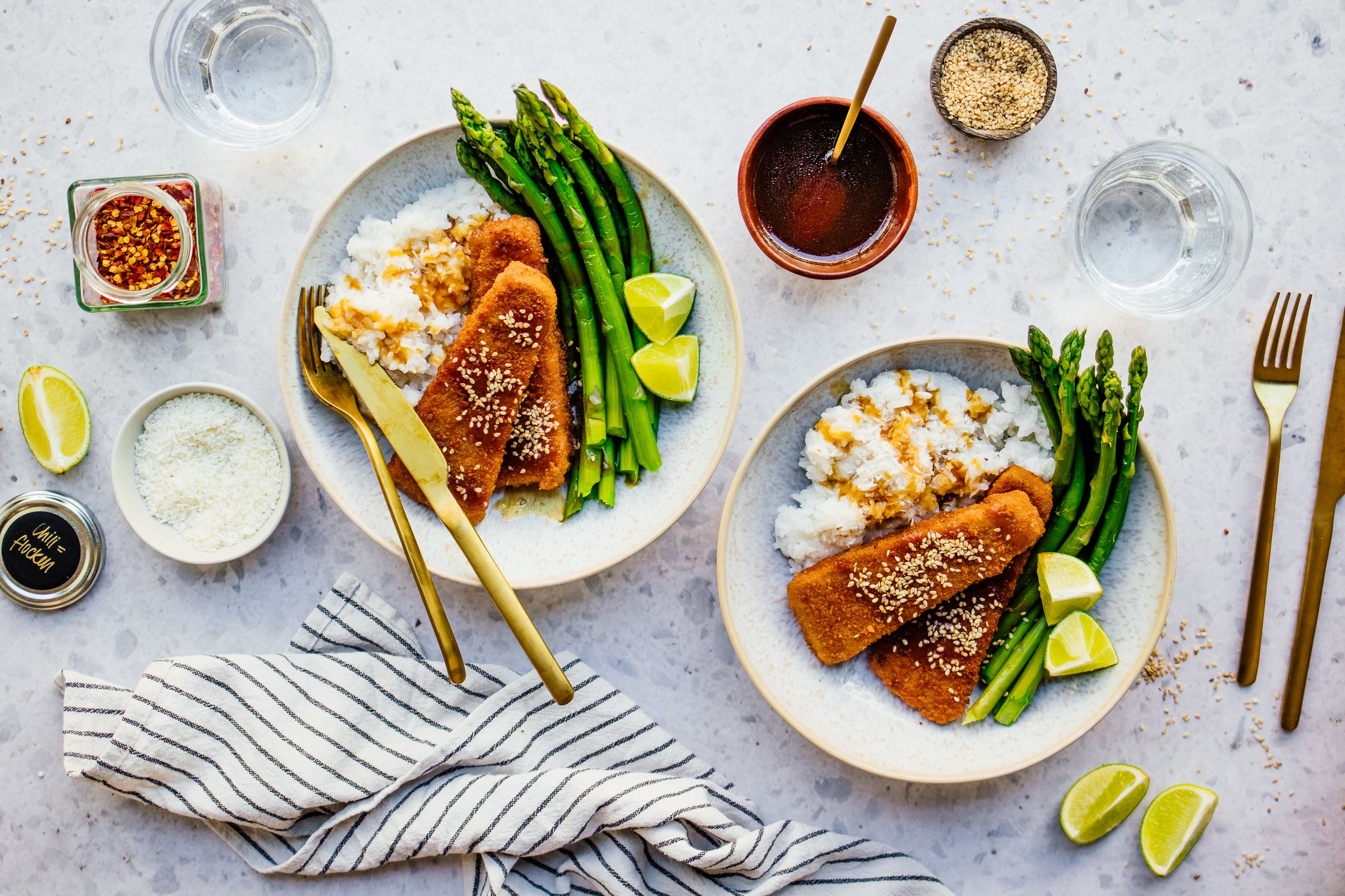 Gedeckter Tisch mit veganem Fisch, Kokosreis, Spargel, Chili, Besteck, Soße, Gläser