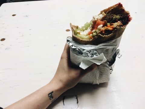hand holding a vegan falafel wrap