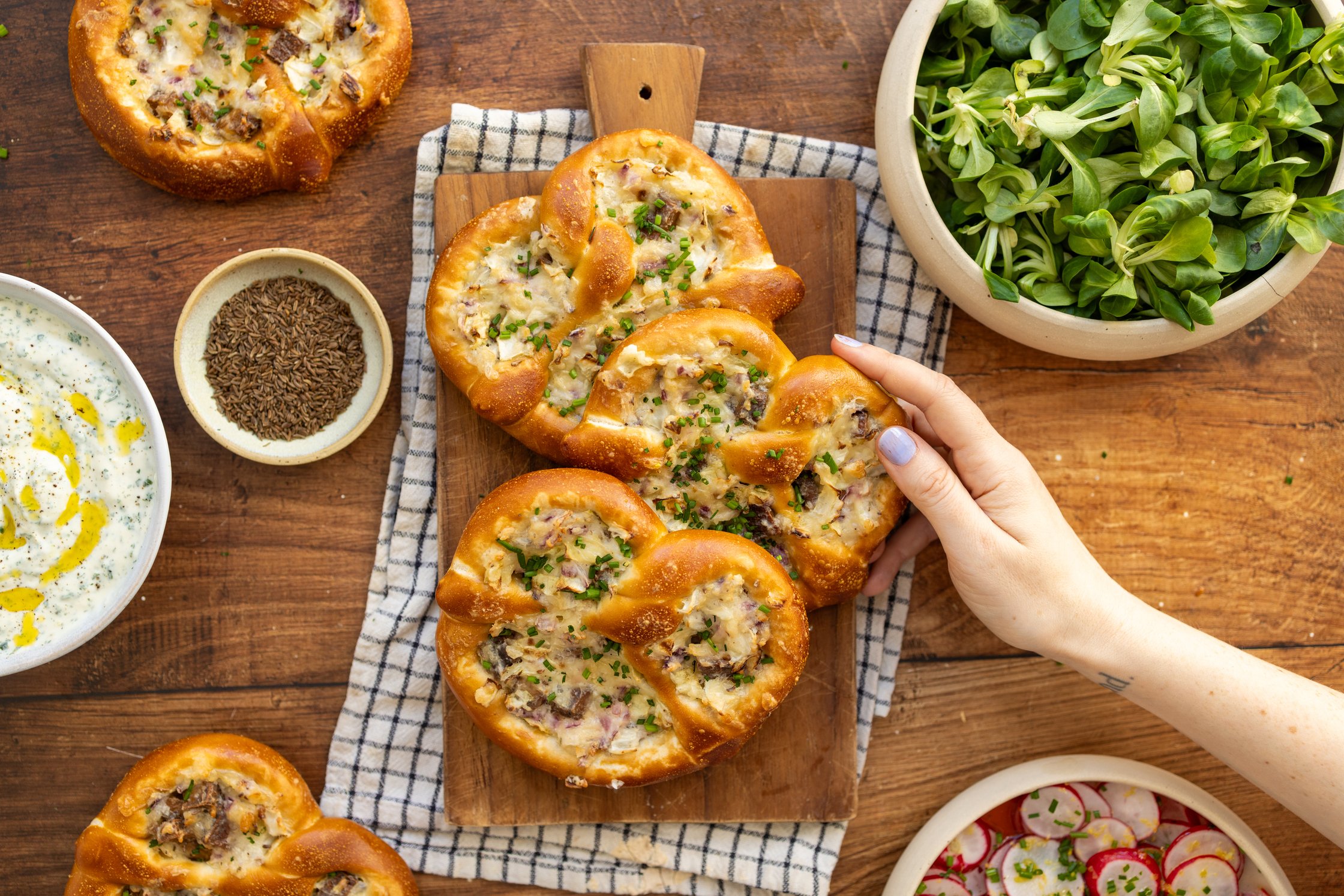 eine hand nimmt sich eine gefüllte kraut-brezel