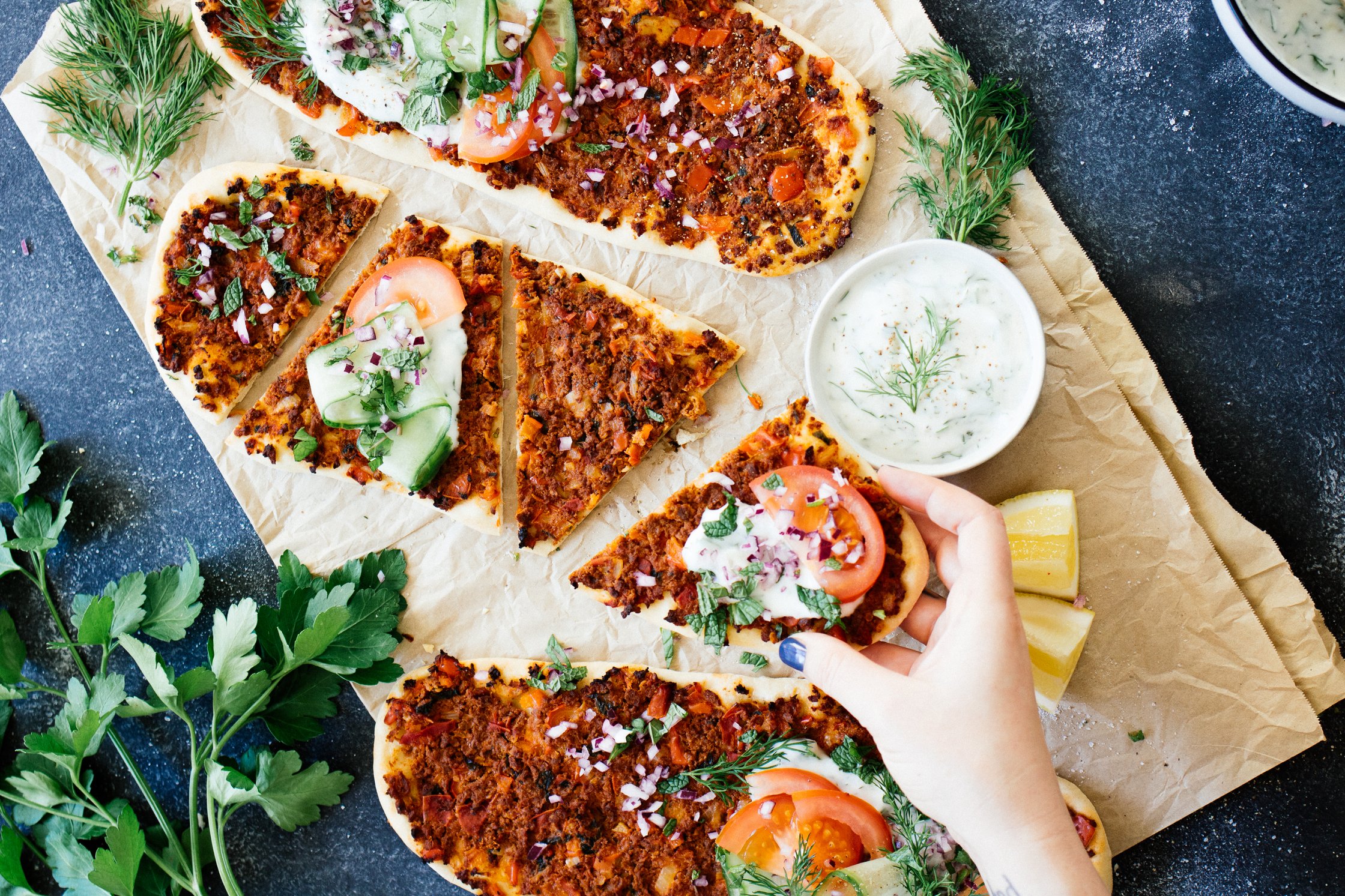 piece of vegan Turkish pizza with herbed yogurt and tomatoes