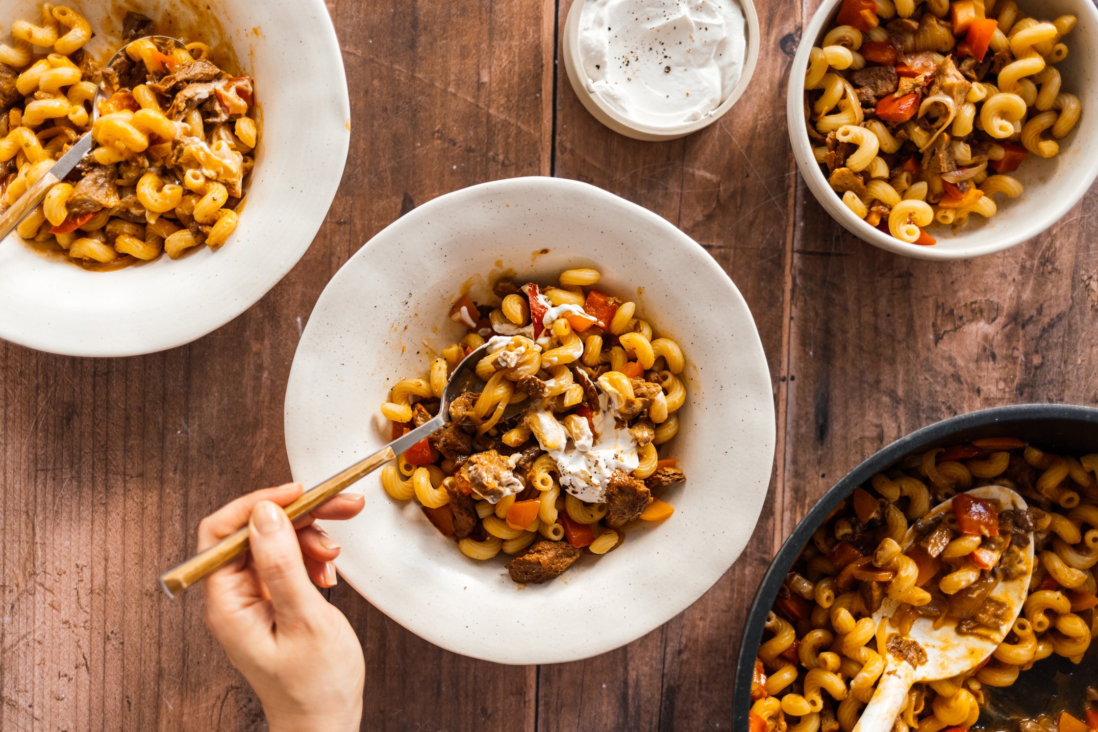 Veganes Paprika-Seitan-Gulasch mit Nudeln ist serviert auf tellern auf einem tisch