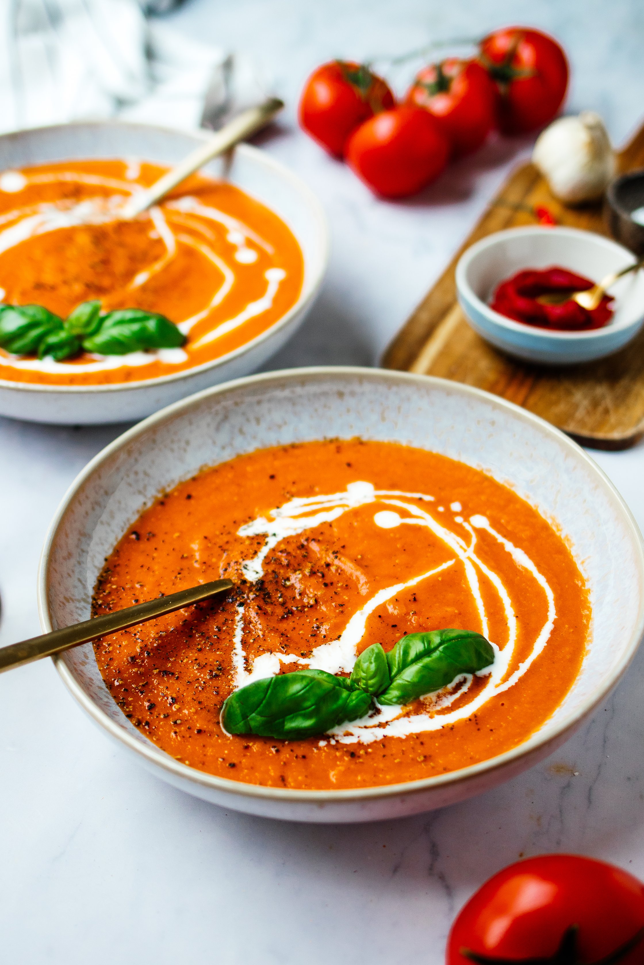 two bowls with vegan tomato soup and basil