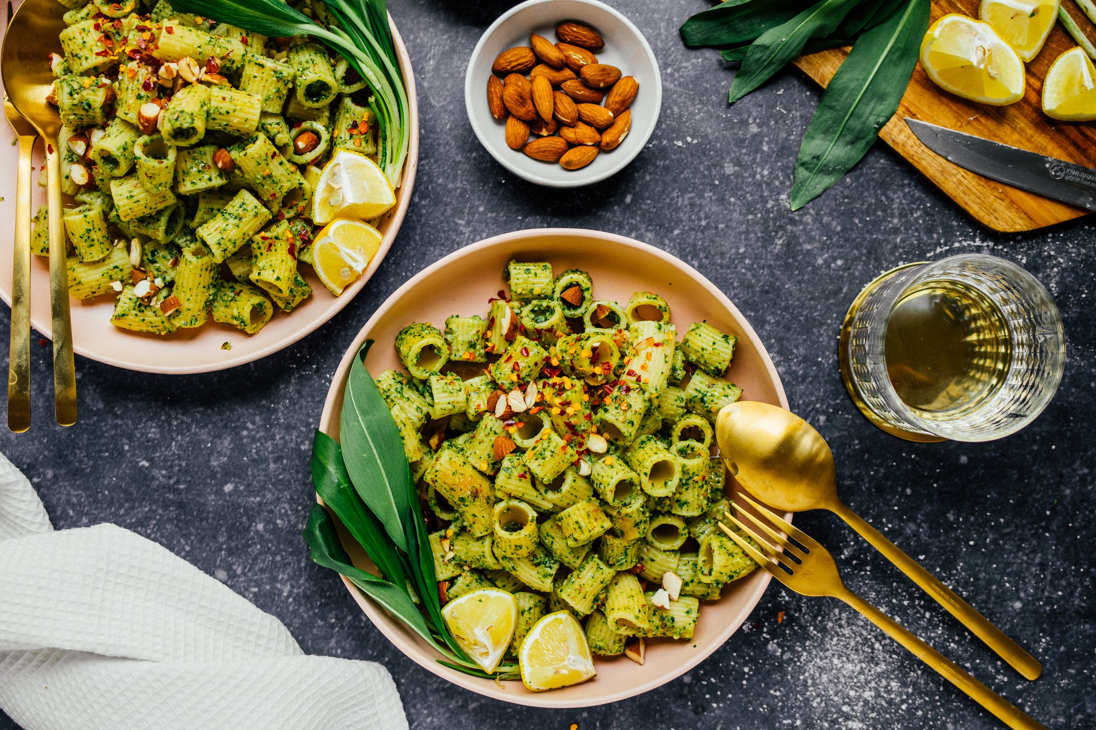 Zwei Teller mit Bärlauchpesto Pasta und gerösteten Mandeln