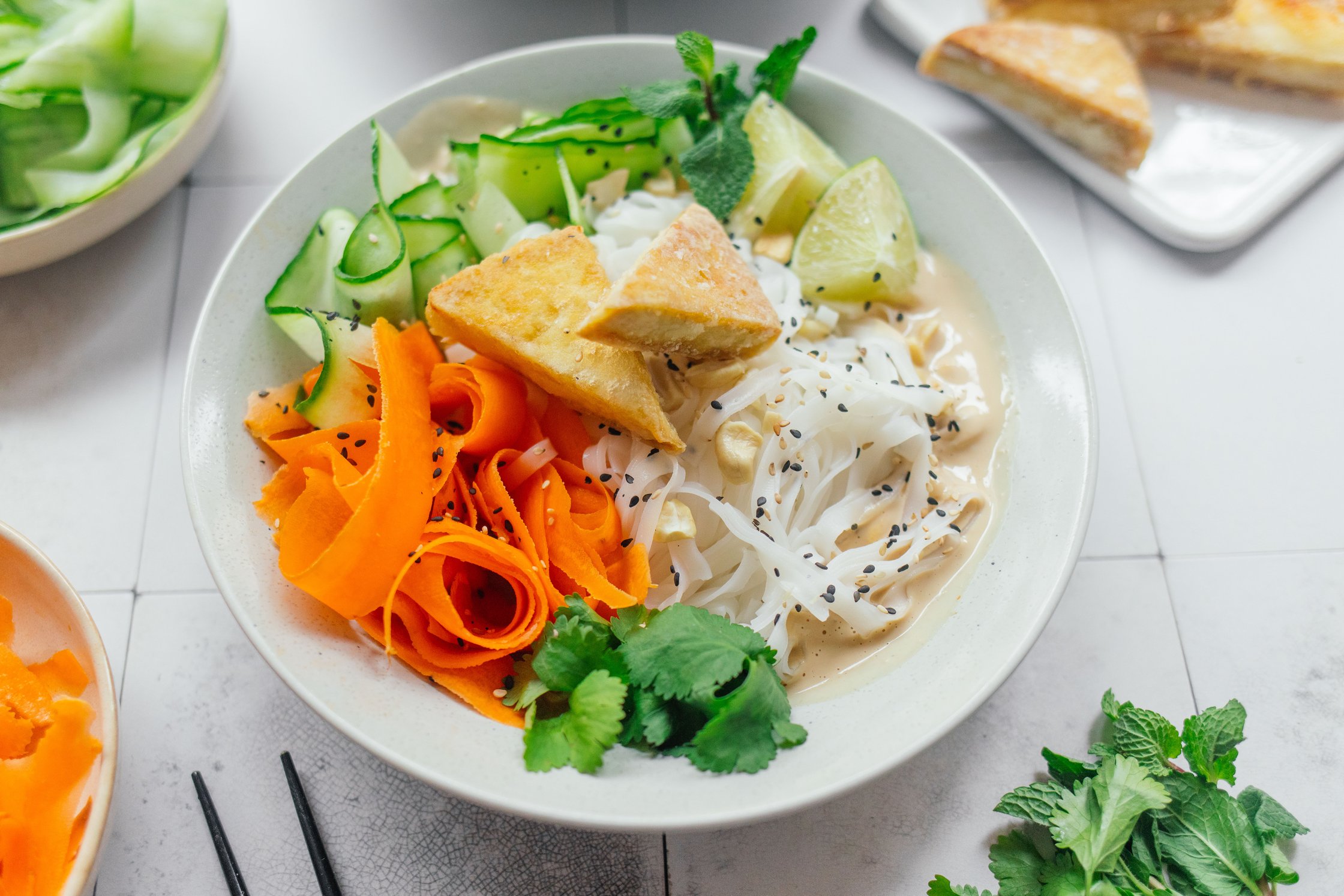 a plate of rice noodles with tofu in peanut sauce
