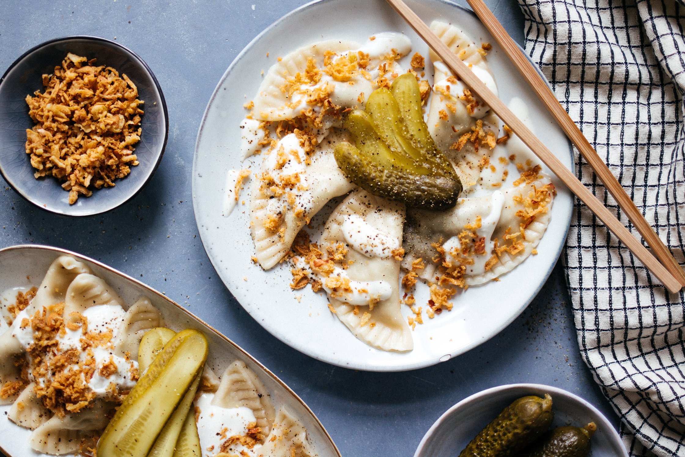 pierogies on a white plate, topped with gherkins