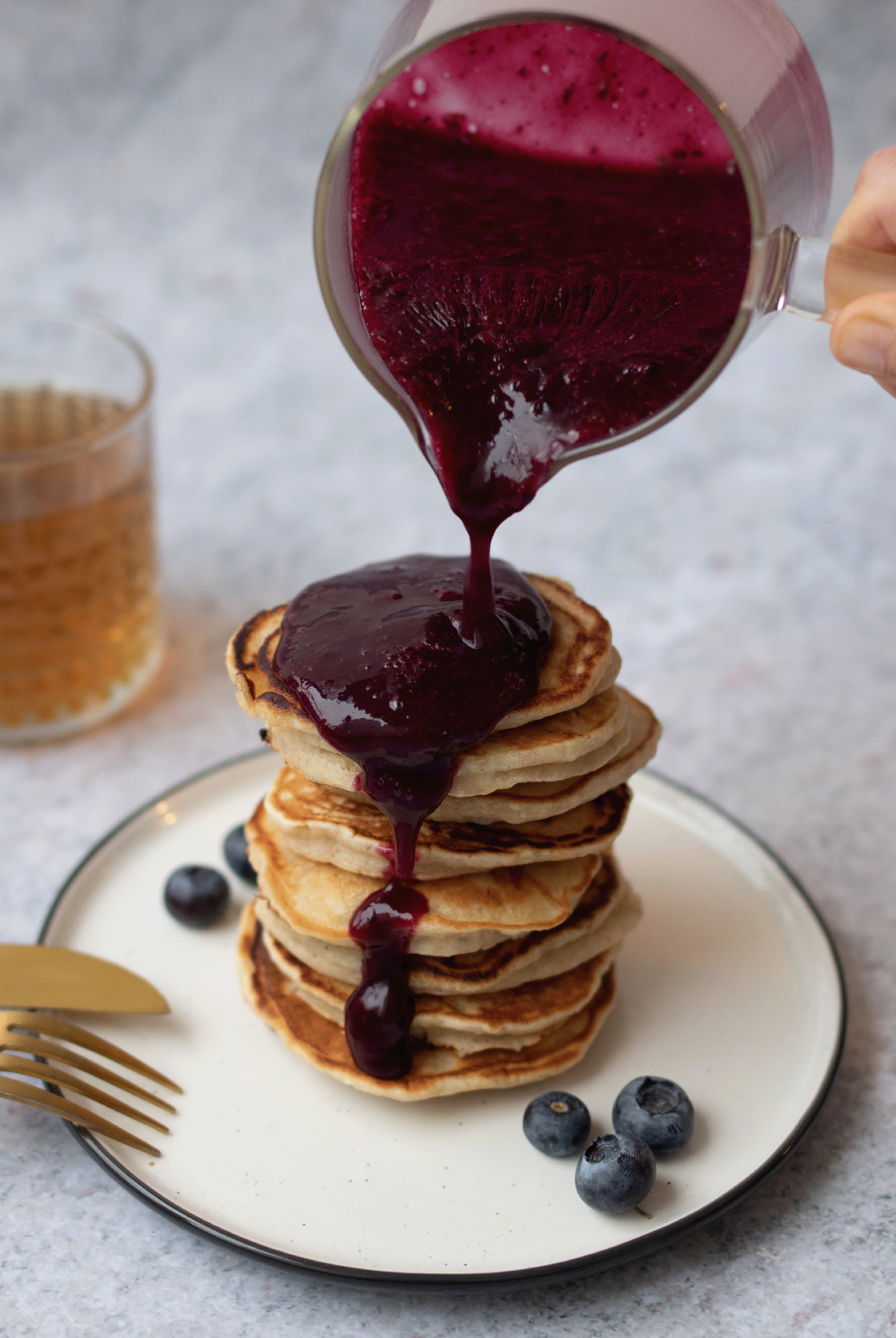 Blaubeersoße wird über Pancakes gegossen