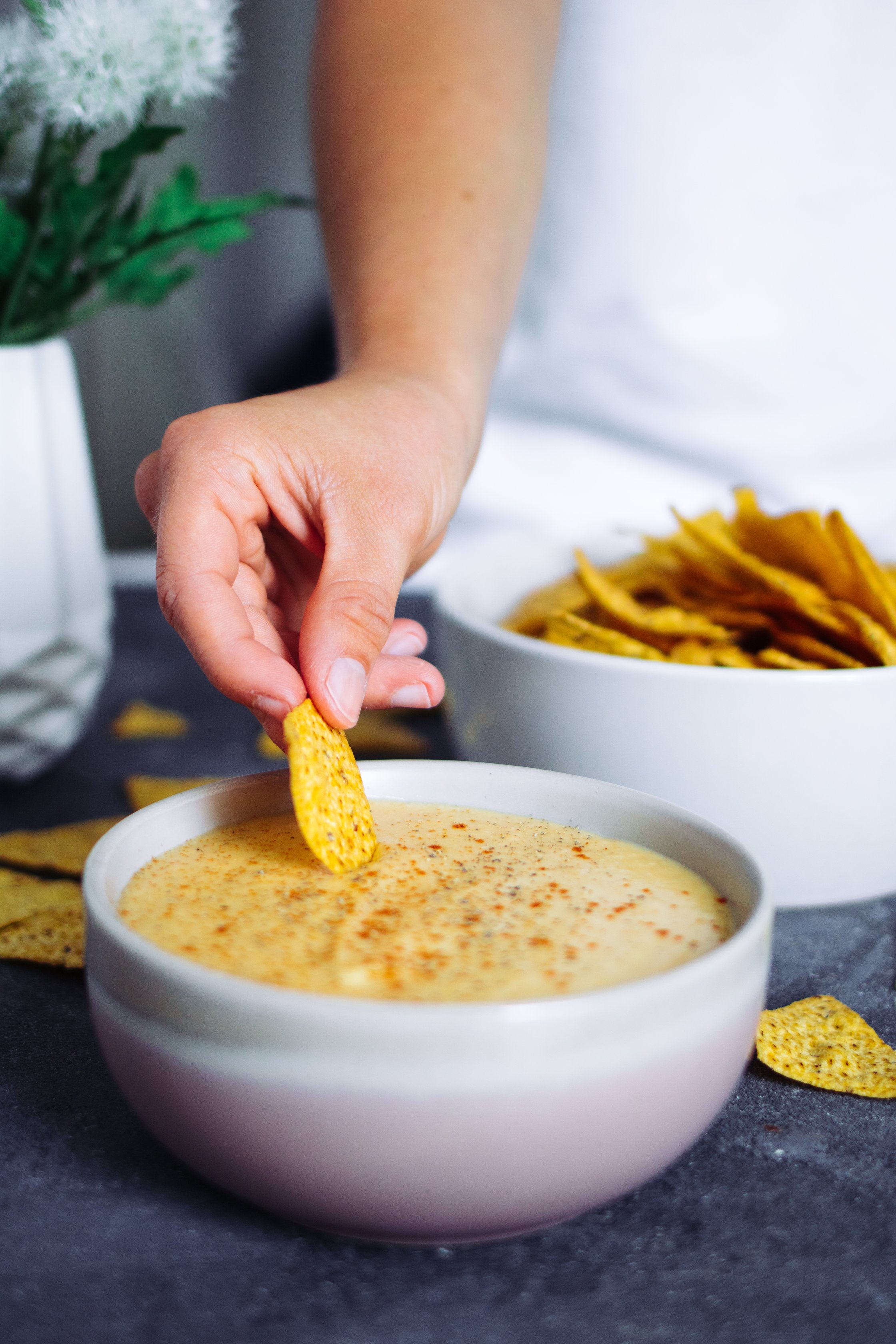 dipping tortilla chip into vegan queso dip