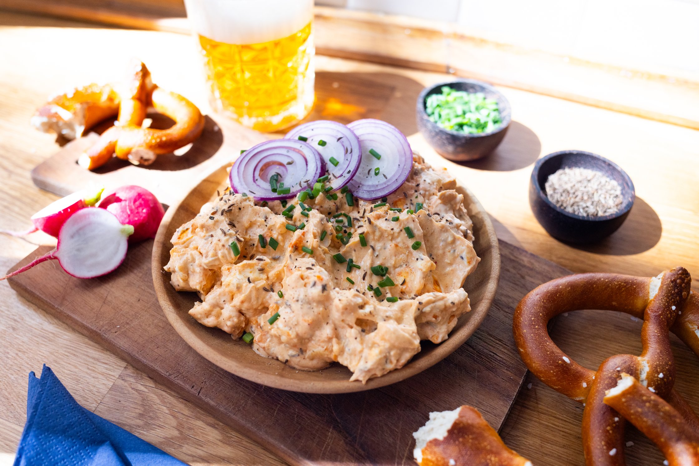 vegan Bavarian cheese obazda on a plate with chives and red onions, a glas with beer