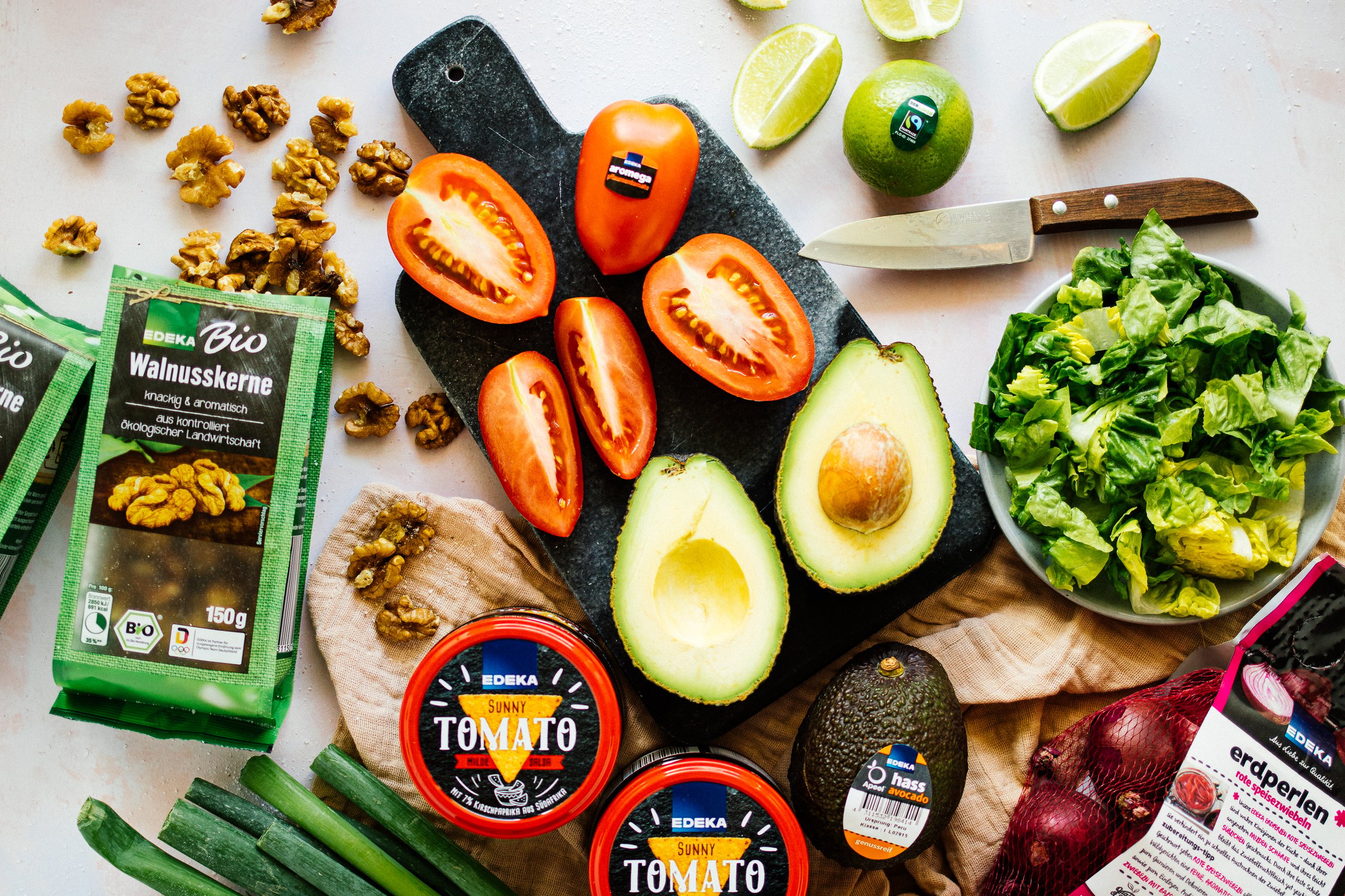 Tomaten, Avocado, Salat und Walnüsse auf einem Schneidebrett